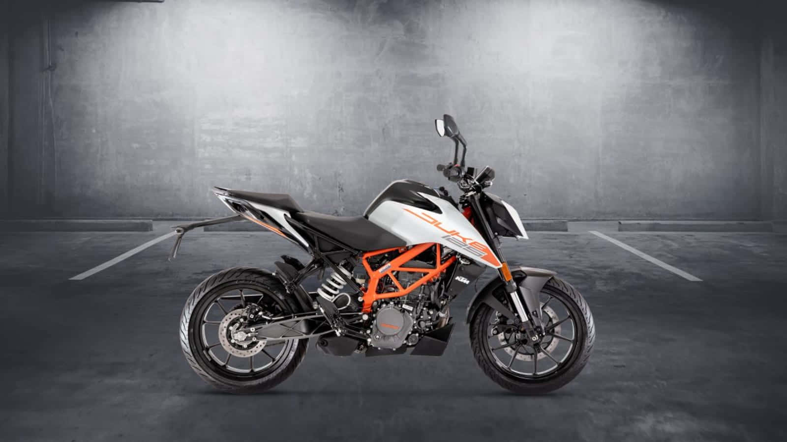 機車 桌布 壁紙 — 一台時尚的橙色和白色KTM Duke機車在極簡風格的混凝土車庫中，搭配戲劇性的聚光燈效果。