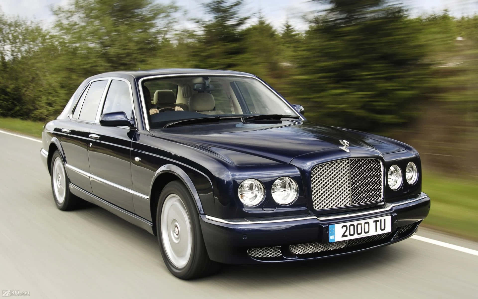 Bentley Arnage 桌布 壁紙 — 一台時尚的海軍藍賓利 Arnage 在林蔭大道上行駛，動態模糊強調速度與奢華。