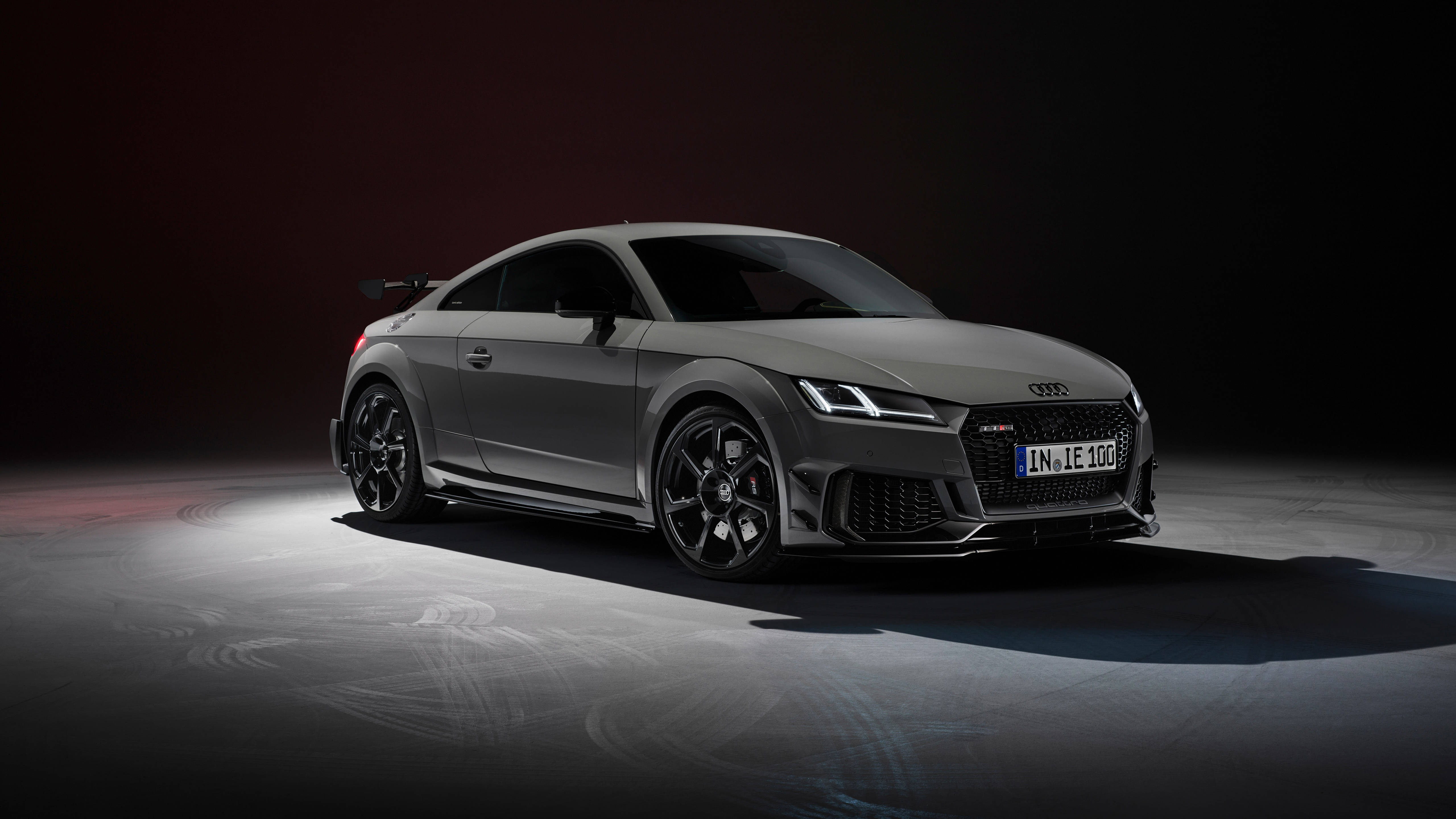 奧迪 桌布 壁紙 — 一台時尚的消光灰色Audi TT RS跑車在黑暗的攝影棚背景下，地板上有輪胎痕跡，燈光效果極具戲劇性。