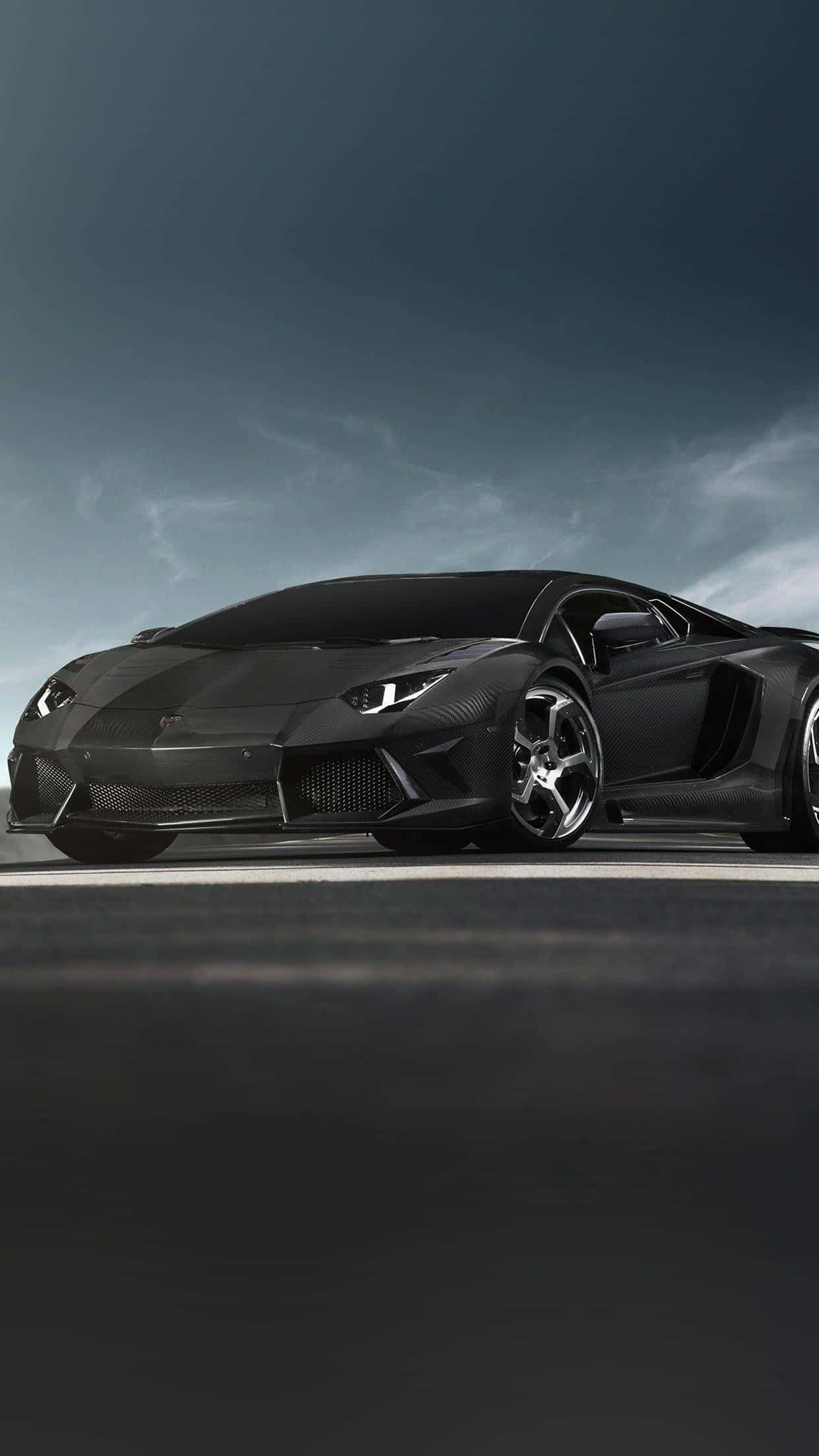 Lamborghini Phone 桌布 壁紙 — 一台時尚的消光黑色藍寶堅尼Aventador停放在昏暗的道路上，天空陰沉多雲。