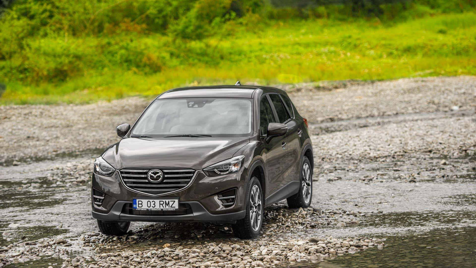 Mazda Cx-5 桌布 壁紙 — 一台時尚的灰色Mazda CX-3 SUV穿越被茂密綠草包圍的淺石溪流。