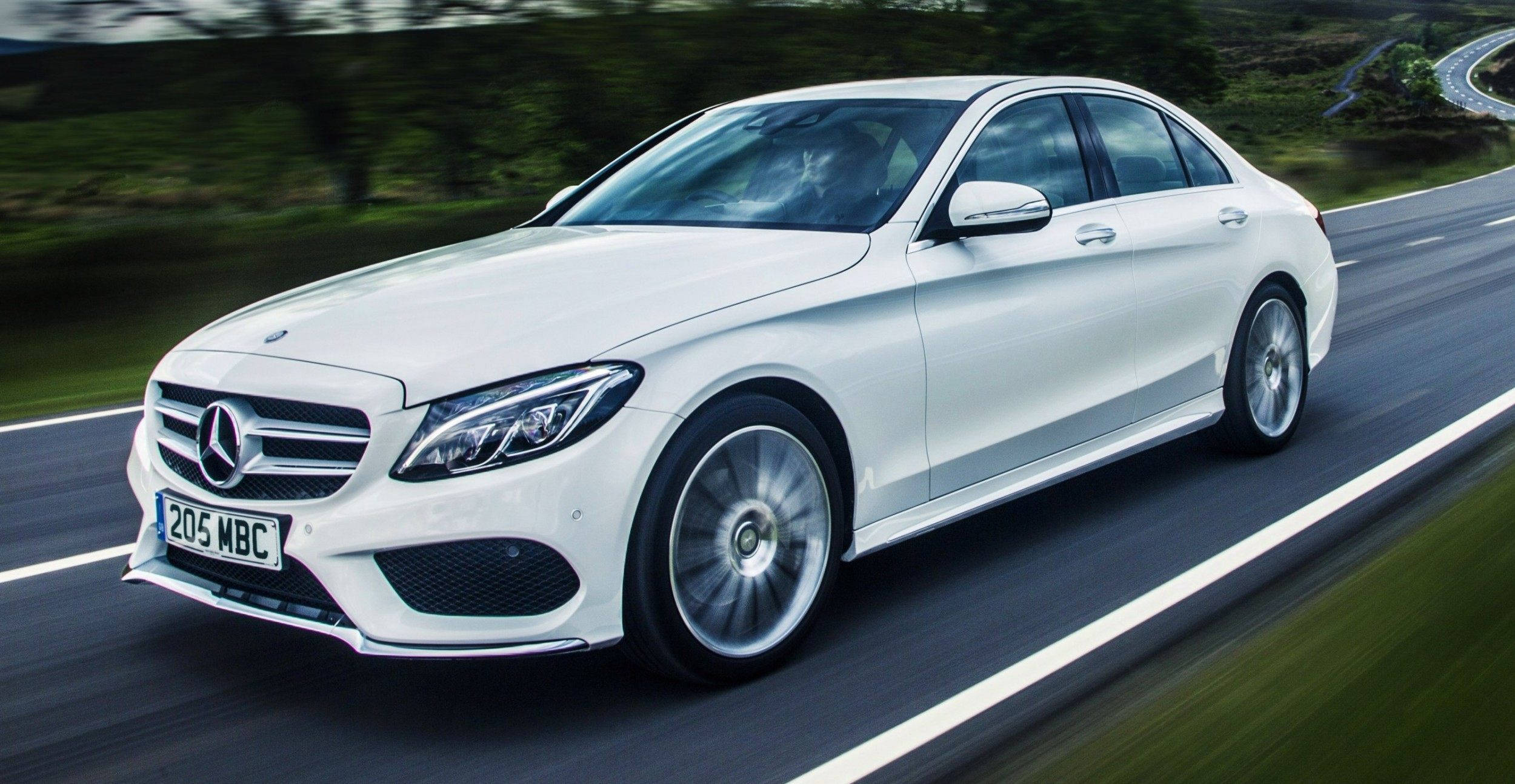 Mercedes Benz C300 桌布 壁紙 — 一台時尚的白色 Mercedes-Benz 轎車在蜿蜒的道路上疾馳，模糊的綠化和瀝青條紋傳達出動感。