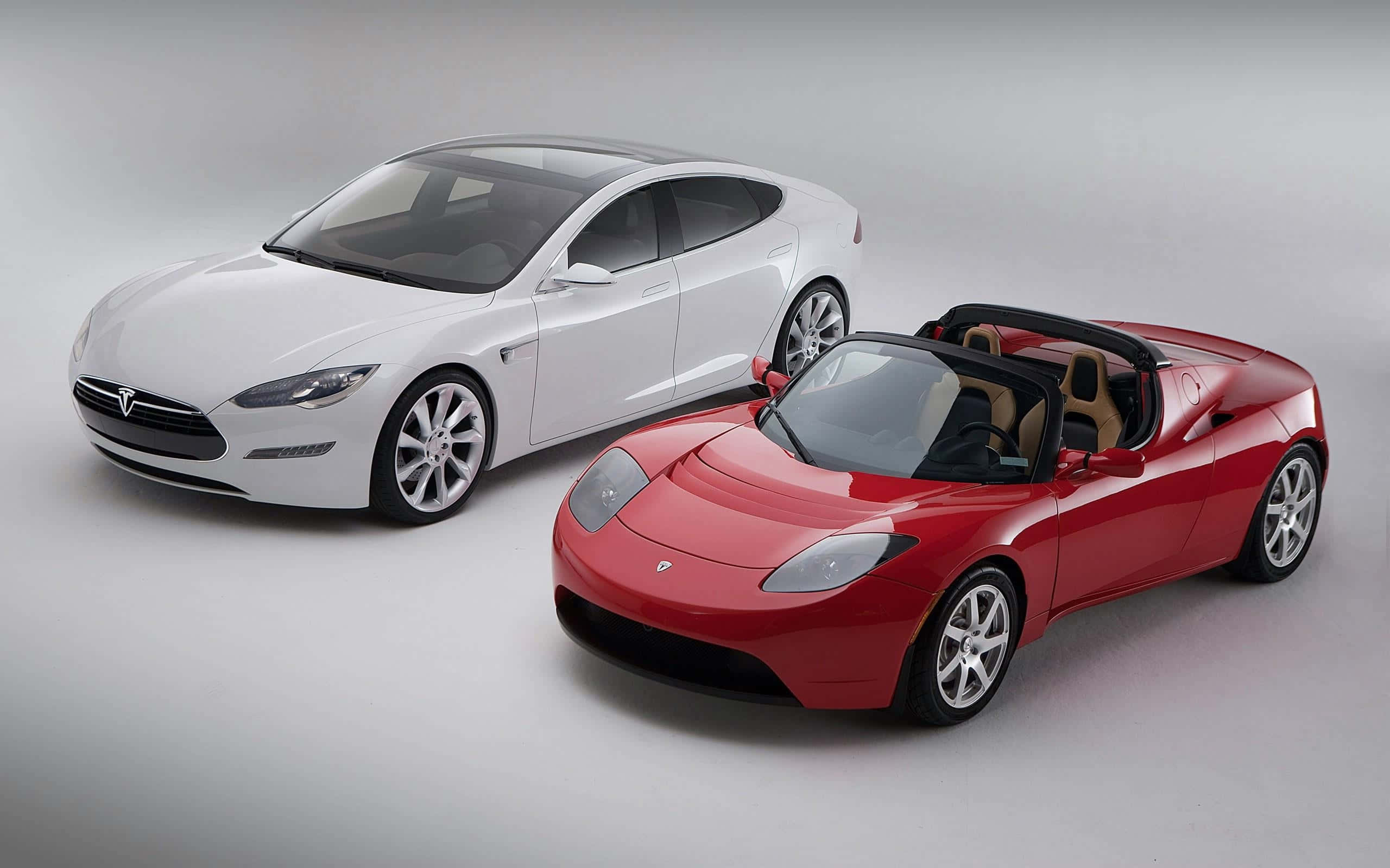 Car Model 桌布 壁紙 — 一台時尚的白色 Tesla Model S 轎車和一輛充滿活力的紅色 Tesla Roadster 敞篷車在簡約的攝影棚地板上並排展示。