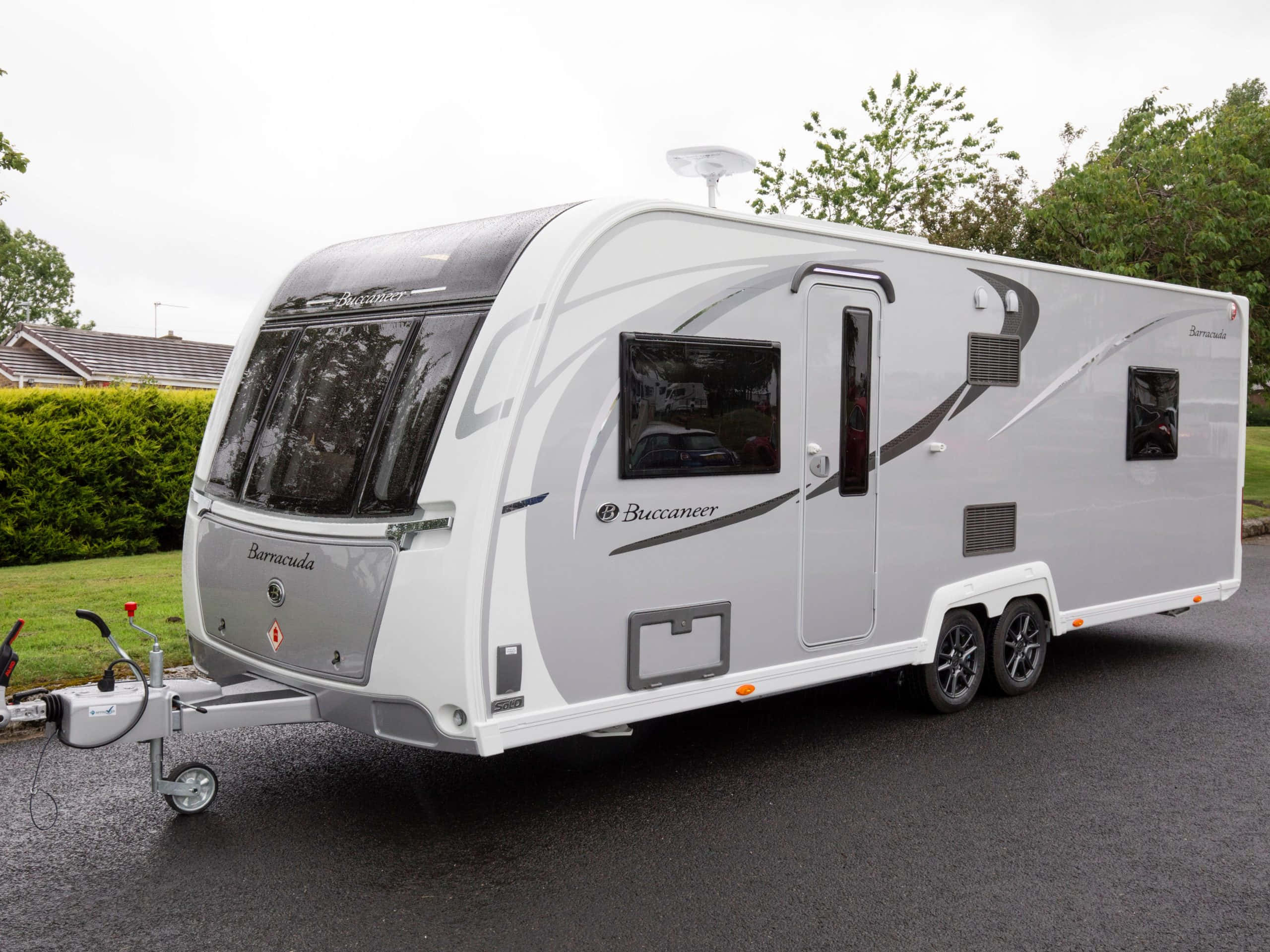 Caravan 桌布 壁紙 — 一台時尚的白色Berracuda露營車，帶有灰色點綴，停在柏油路上，旁邊是綠色樹籬，天空多雲。