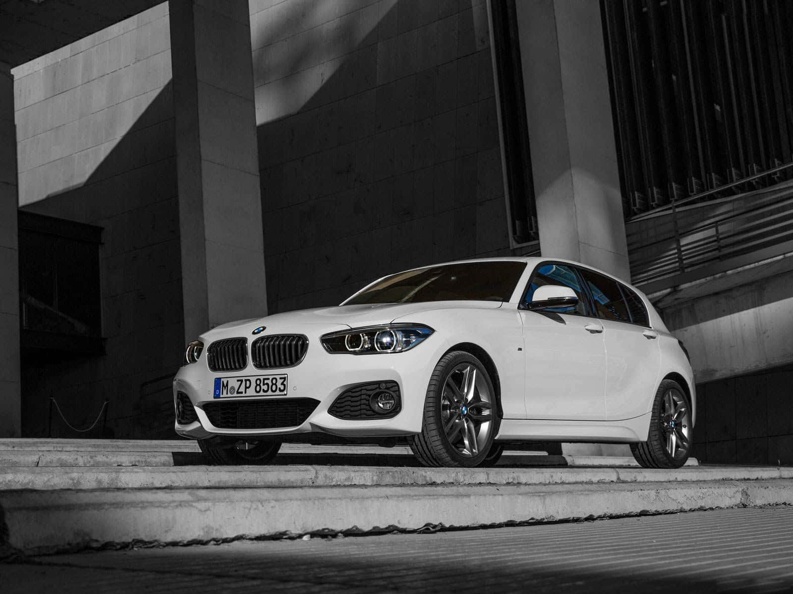 Bmw 1 Series 桌布 壁紙 — 一台時尚的白色BMW 1系列掀背車停在混凝土階梯上，背景為現代建築，光影對比強烈。