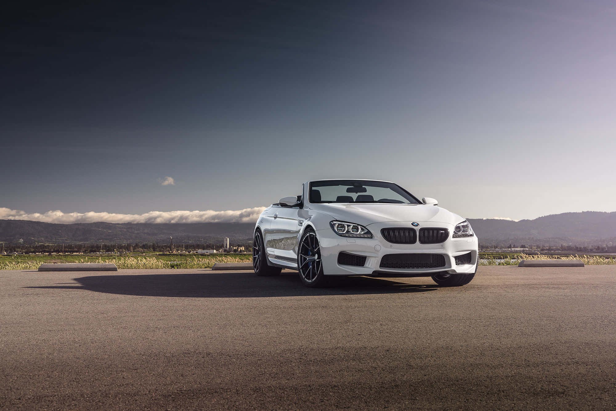 Bmw M6 桌布 壁紙 — 一台時尚的白色BMW M6敞篷車停在柏油路上，背景是晴朗天空下的遠山和白雲。
