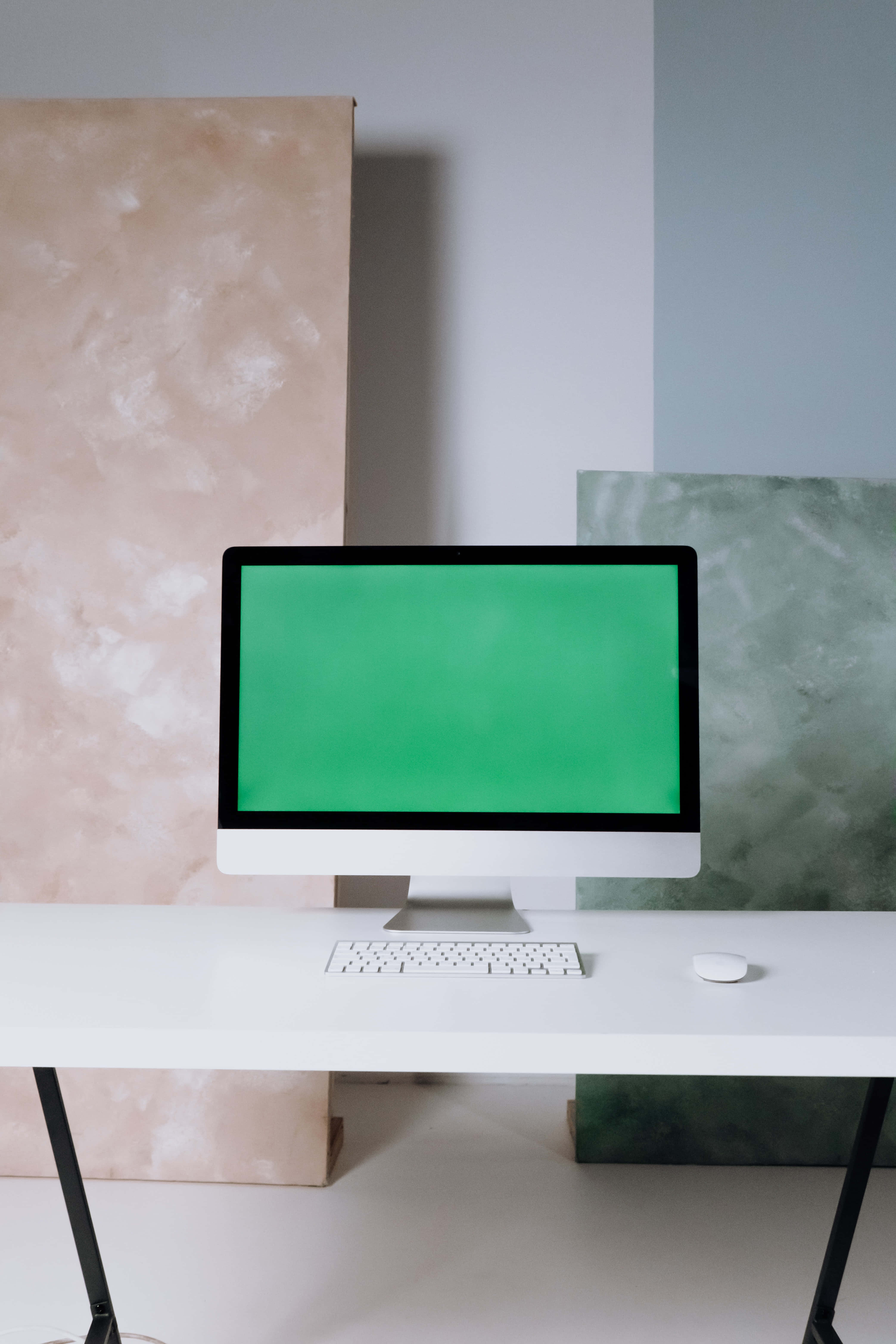 Green Screen 桌布 壁紙 — 一台時尚的白色iMac配綠色螢幕，放置在簡約風格的書桌上，兩側是帶紋理的米色和綠色牆板。