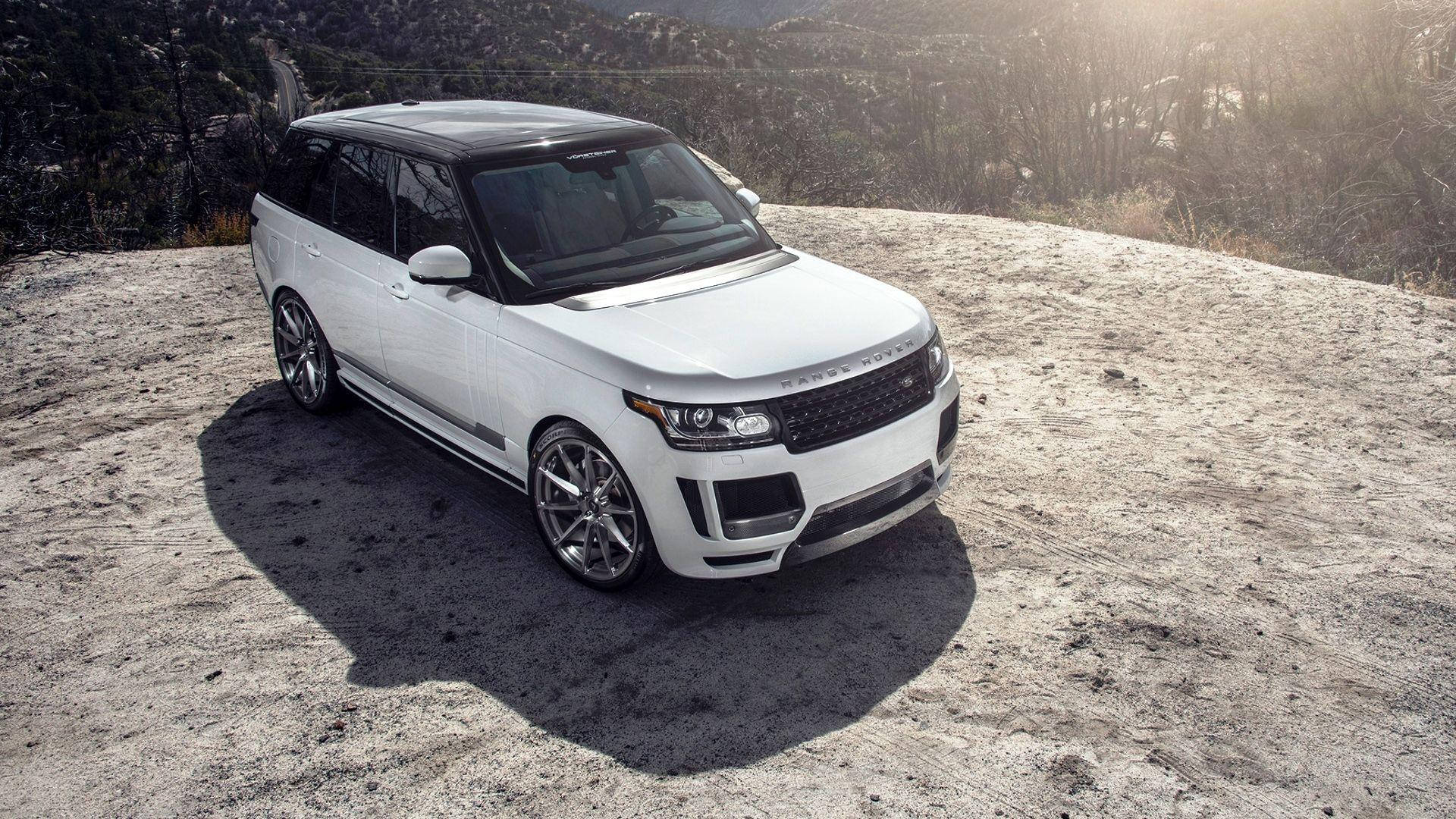 4K 桌布 壁紙 — 一台時尚的白色Range Rover SUV停放在陽光明媚、佈滿乾燥灌木和遠處山脈的岩石山坡上。