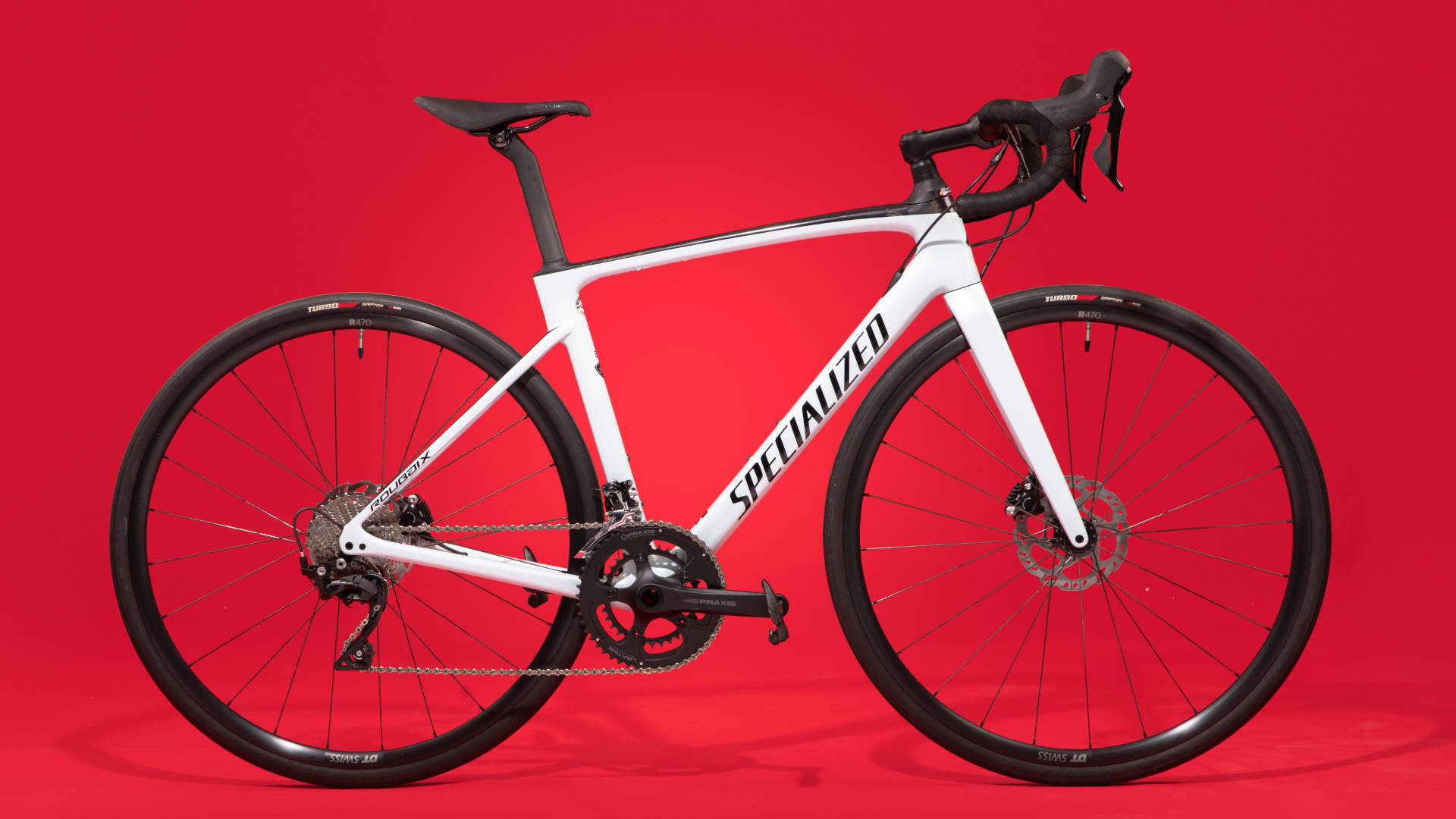 腳踏車 桌布 壁紙 — 一台時尚的白色Specialized公路自行車，帶有黑色點綴，矗立在搶眼的紅色工作室背景前。