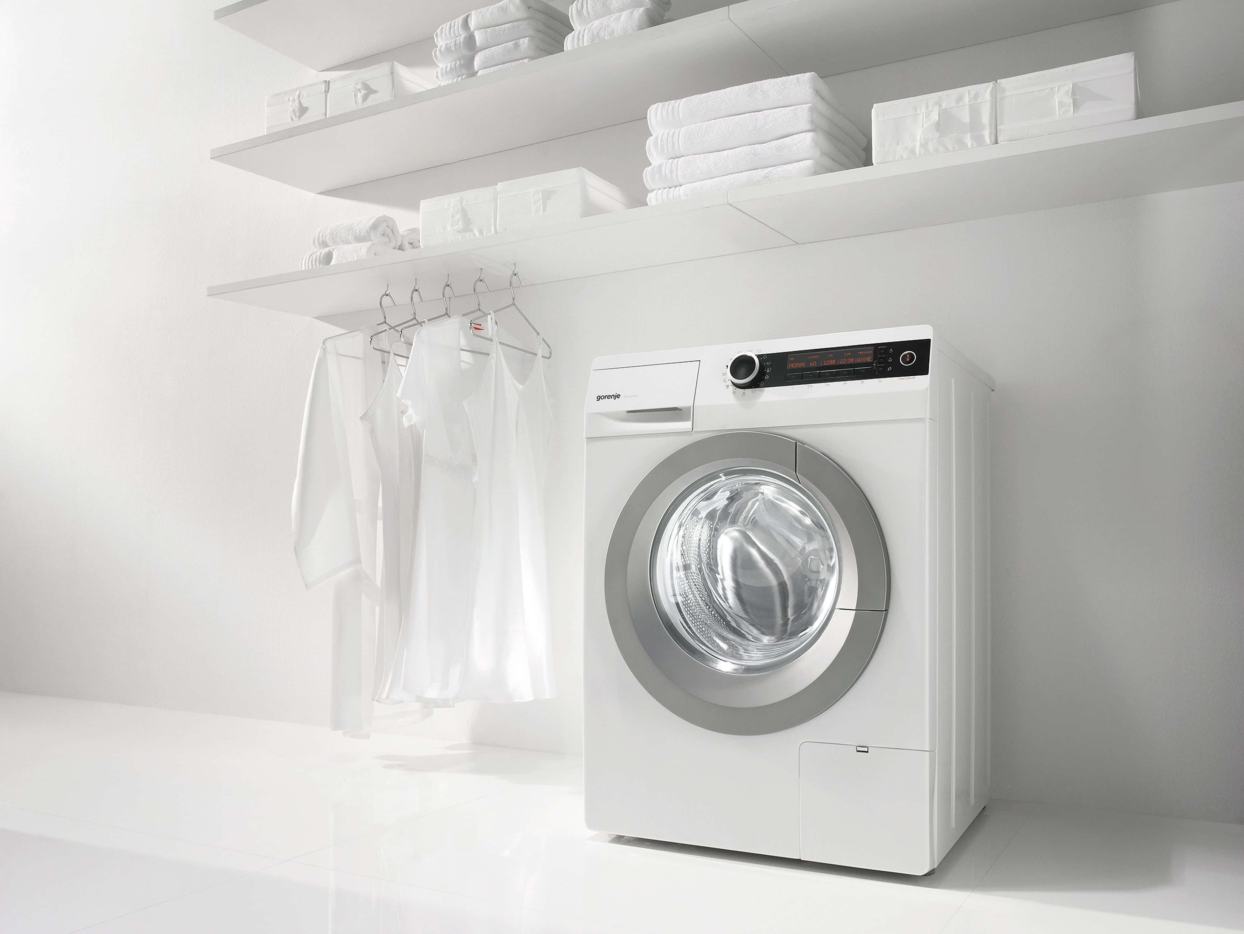 Laundry Room 桌布 壁紙 — 一台時尚的白色前置式洗衣機放置在簡約的洗衣房中，掛著白色衣物，浮動層架上疊放著毛巾。