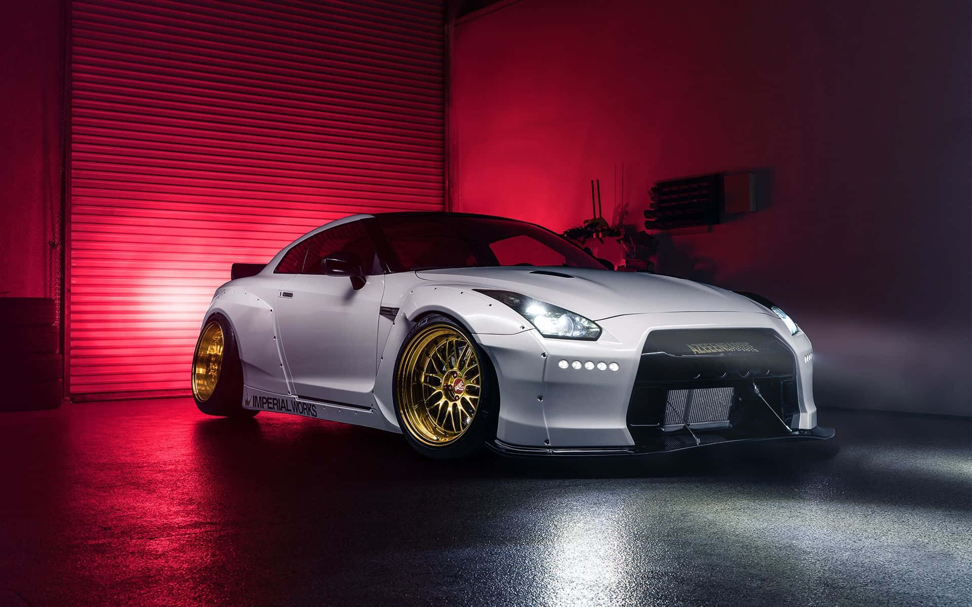 Gtr 桌布 壁紙 — 一台時尚的白色日產GT-R搭配金色輪圈，在昏暗車庫中於戲劇性的紅光下閃耀。
