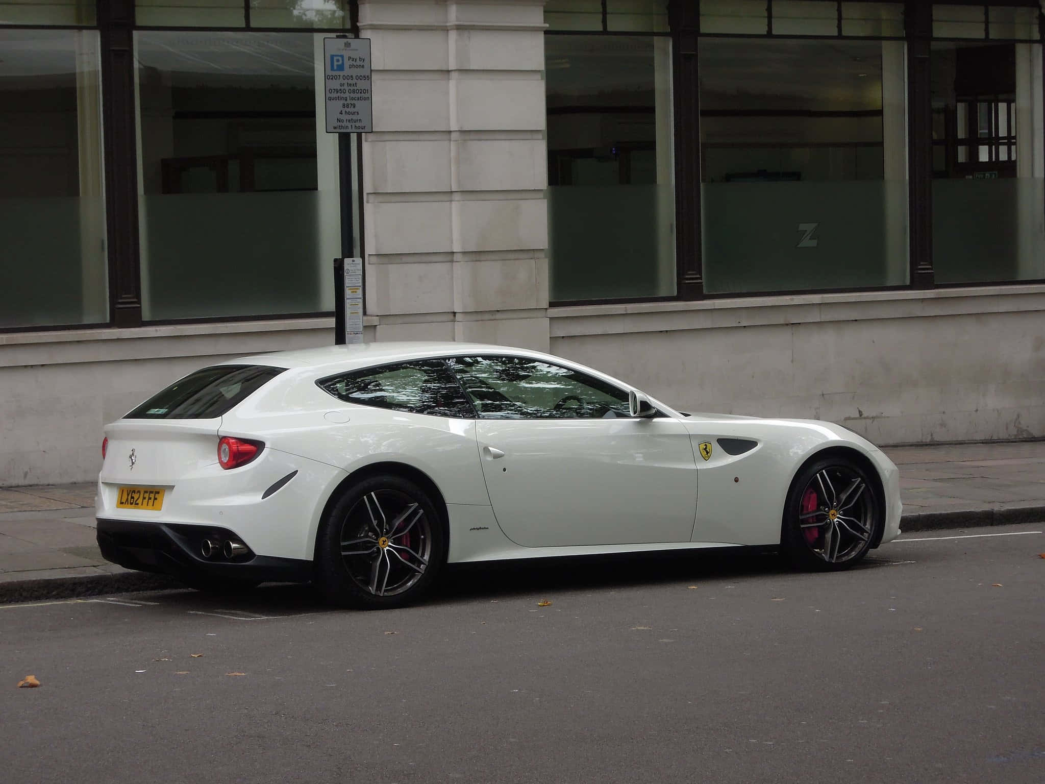 Ferrari Ff 桌布 壁紙 — 一台時尚的白色法拉利FF停放在城市街道上，旁邊是一棟帶有大窗戶的現代建築。