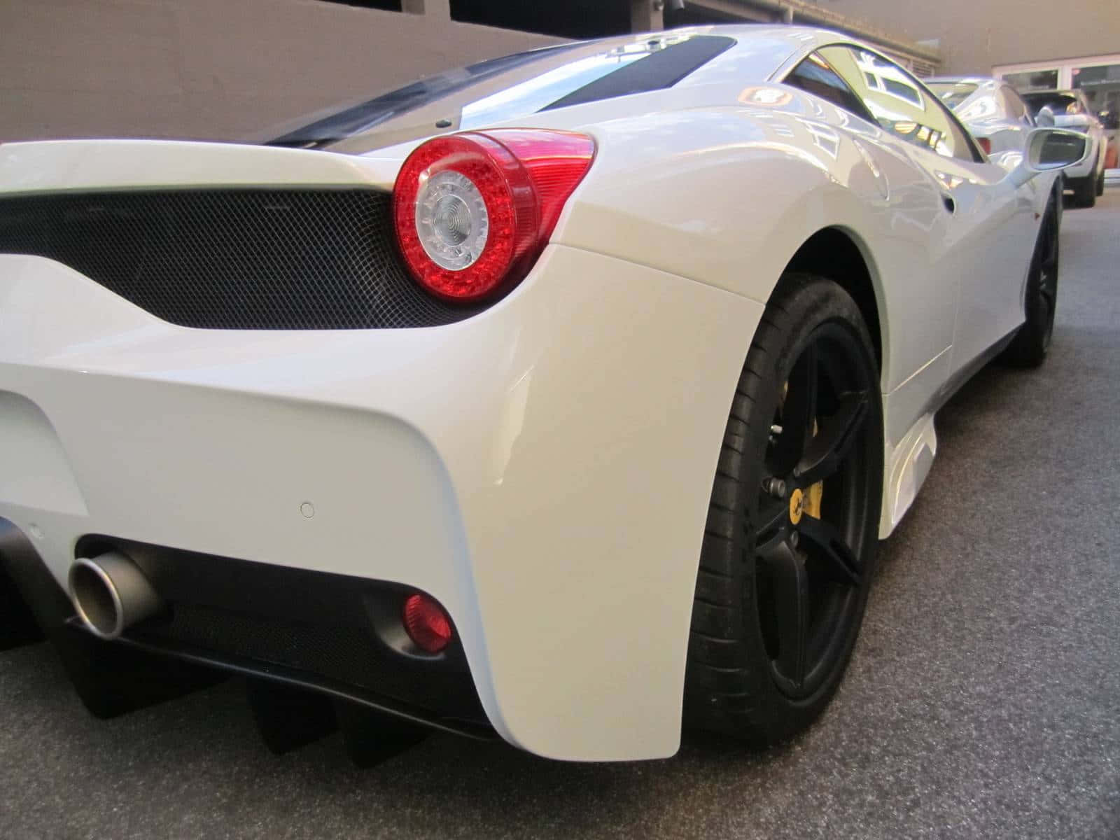 Ferrari 458 Speciale 桌布 壁紙 — 一台時尚的白色法拉利跑車，帶有黑色飾邊和紅色尾燈，停放在灰色地板的室內。