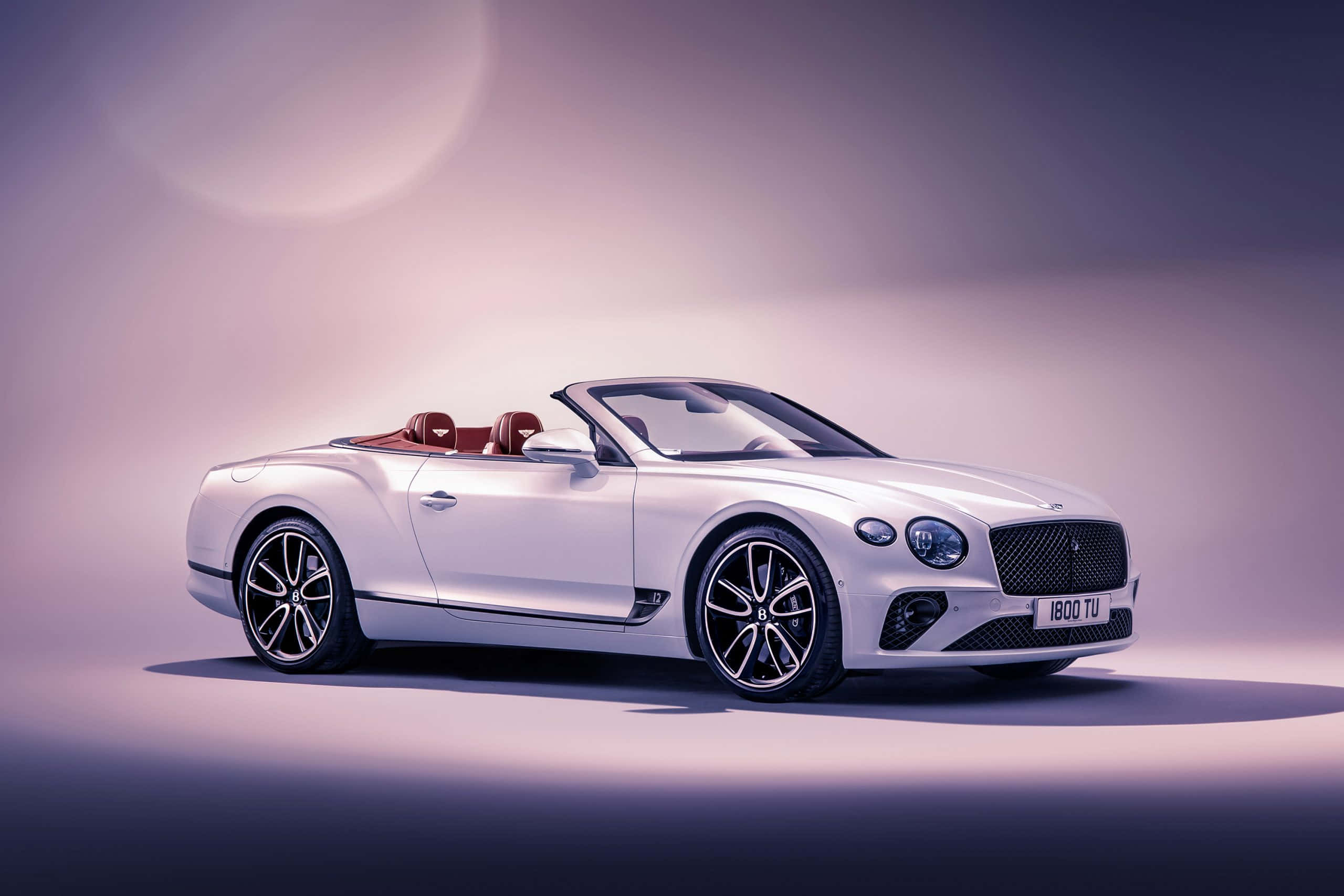 Bentley Continental Gt Convertible 桌布 壁紙 — 一台時尚的白色賓利敞篷車配紅色真皮座椅，在柔和的紫色漸變工作室背景前展示。