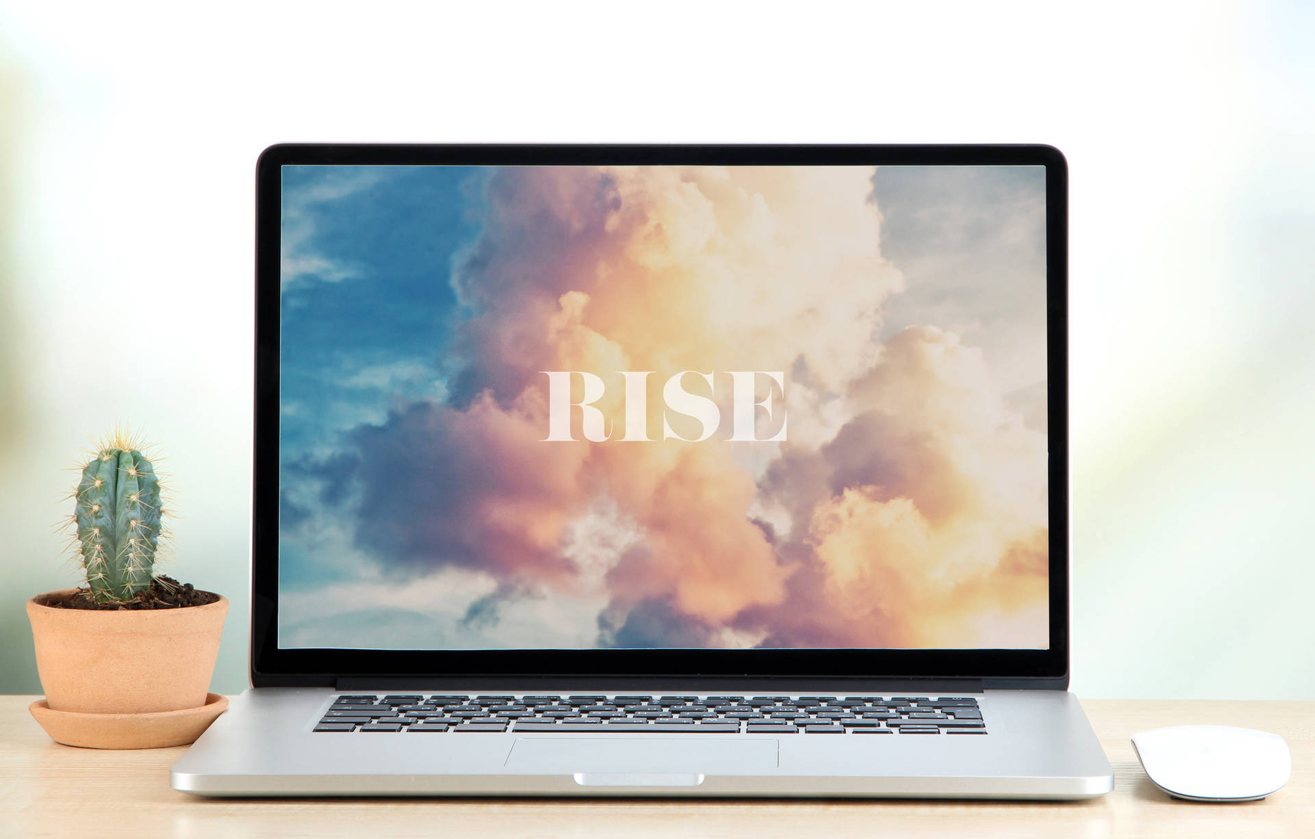 筆記型電腦螢幕顯示「RISE」，背景是日落天空，桌上有一盆仙人掌。 — 美學語錄動圖 壁紙