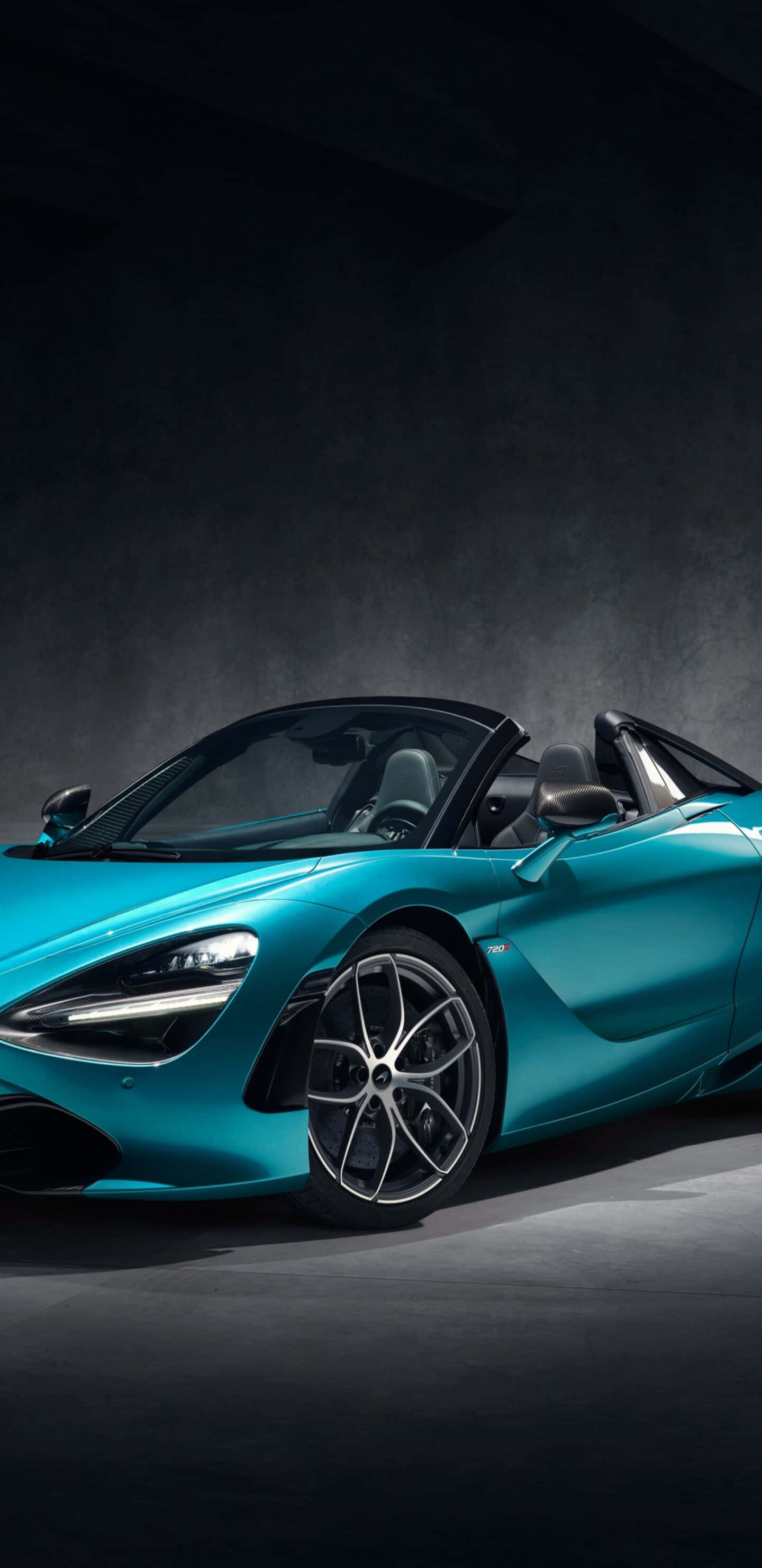 Pixel 3xl 桌布 壁紙 — 一台時尚的藍綠色McLaren 720S Spider敞篷跑車在戲劇性的攝影棚燈光下，於深色紋理背景前閃閃發光。