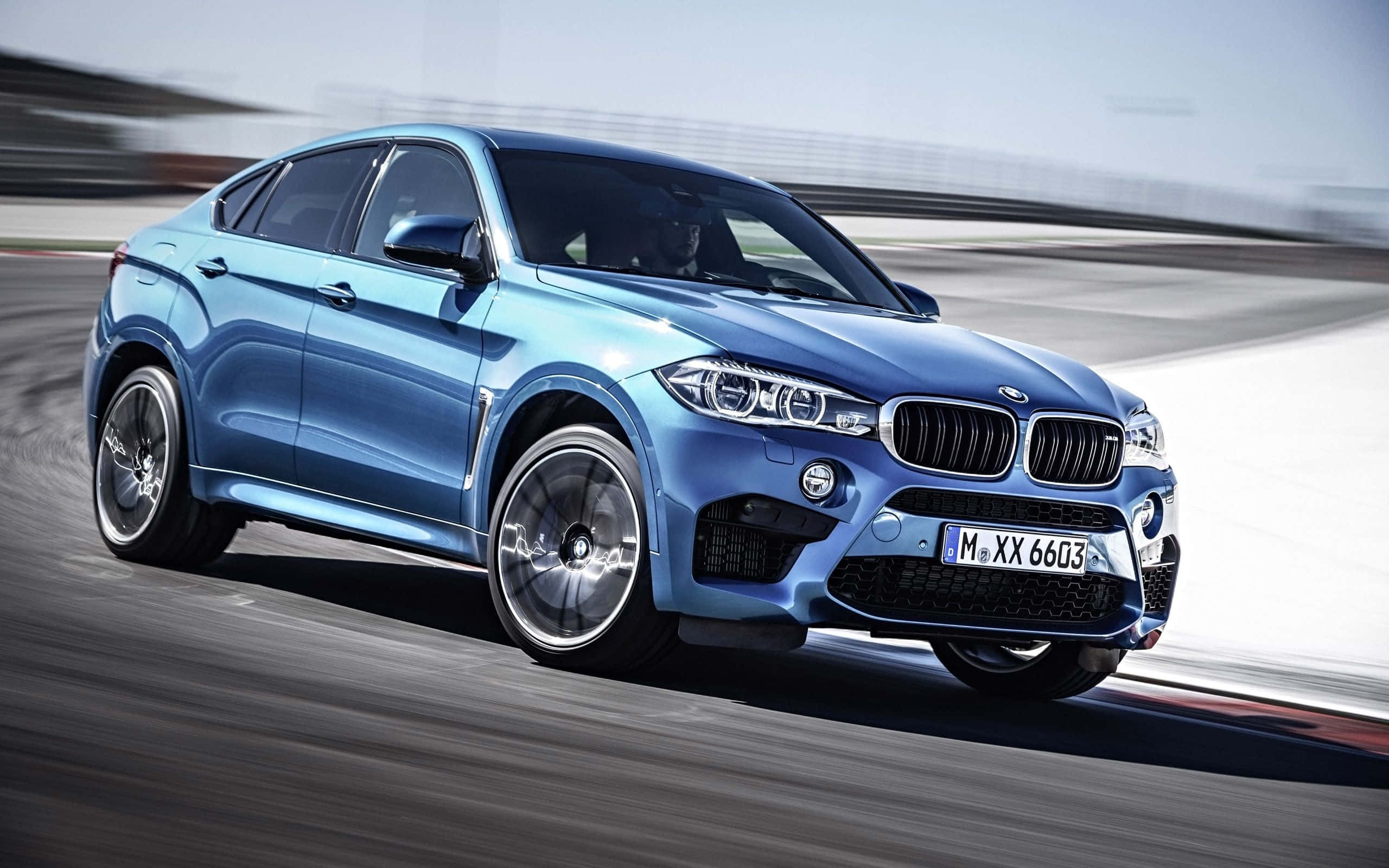 Bmw X6 桌布 壁紙 — 一台時尚的藍色BMW X6 M在賽道上疾馳，動態模糊效果突顯其卓越性能。