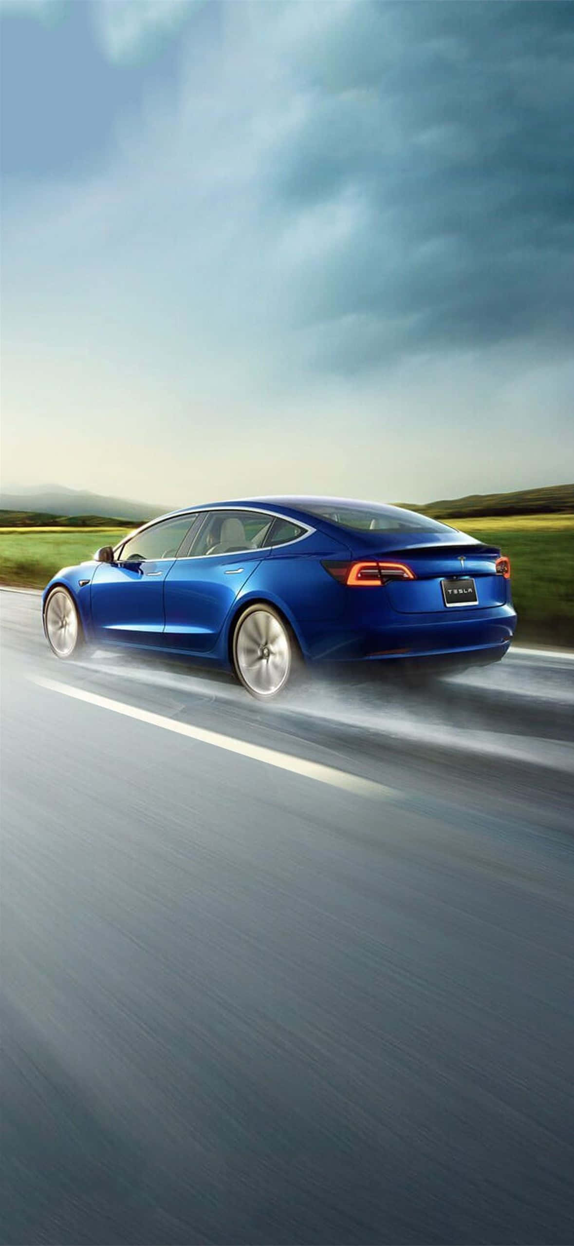 Tesla iPhone 桌布 壁紙 — 一台時尚的藍色Tesla Model 3在陰天天空下沿著蜿蜒的道路疾馳，帶有模糊的動態效果。