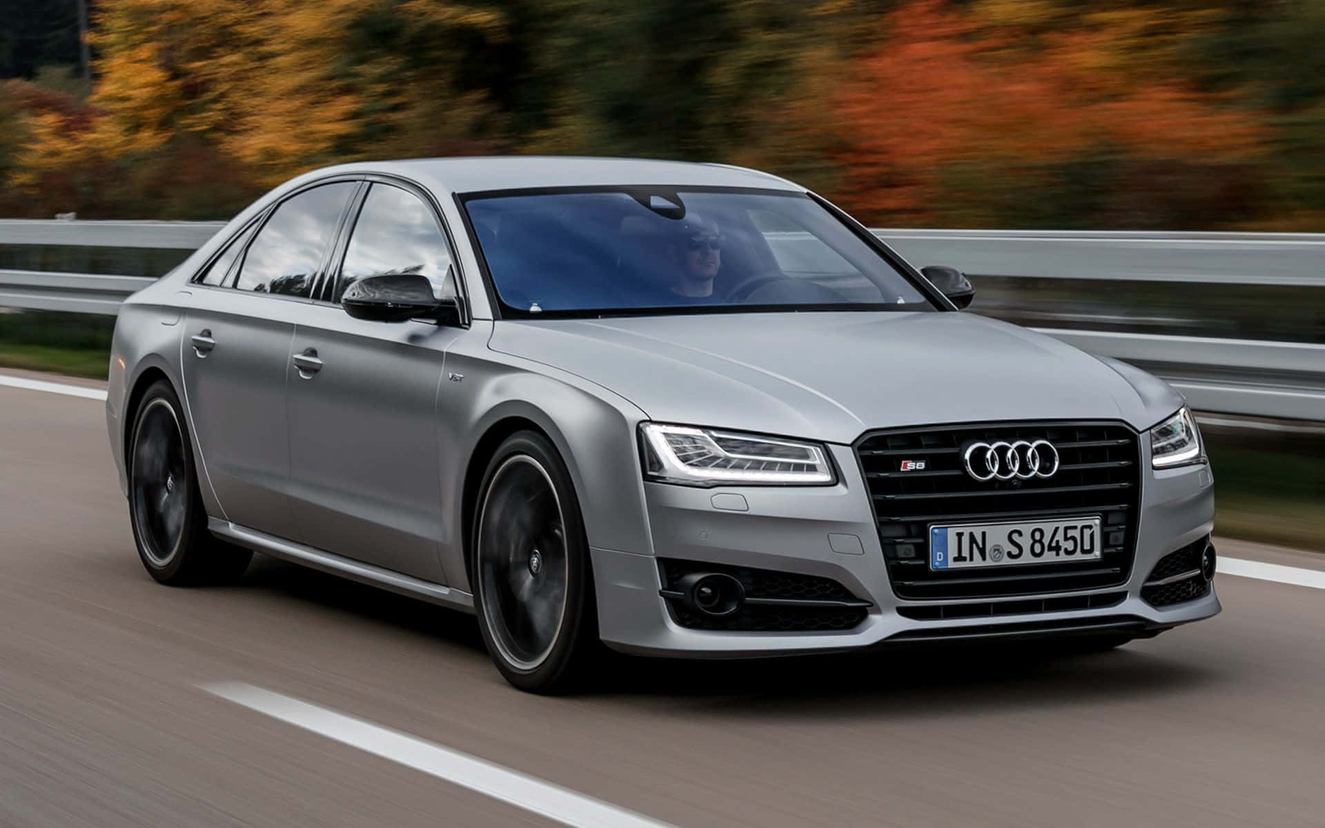 Audi S8 桌布 壁紙 — 一台時尚的銀色 Audi S8 轎車在高速公路上奔馳，背景中的秋葉模糊不清。