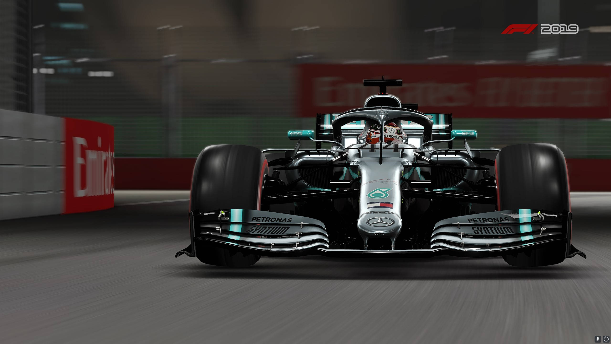 F1 2019 壁紙 桌布 壁紙 — 一台時尚的銀色和藍綠色一級方程式賽車在賽道上奔馳，背景有動態模糊和贊助商橫幅。