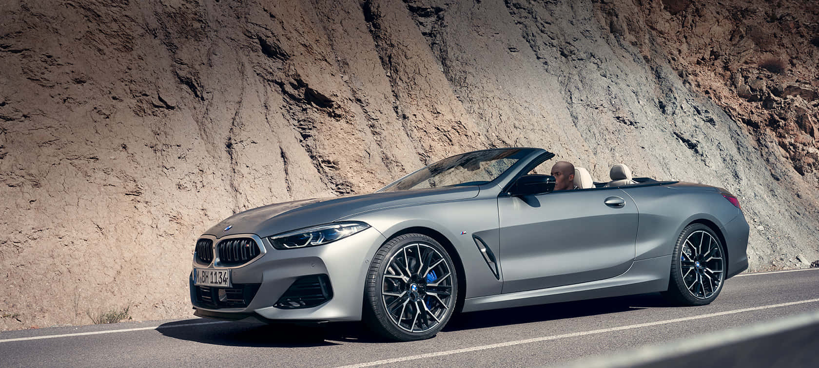 BMW 動圖 桌布 壁紙 — 一台時尚的銀色寶馬敞篷車沿著蜿蜒的山路行駛，司機享受著敞篷駕駛的樂趣。