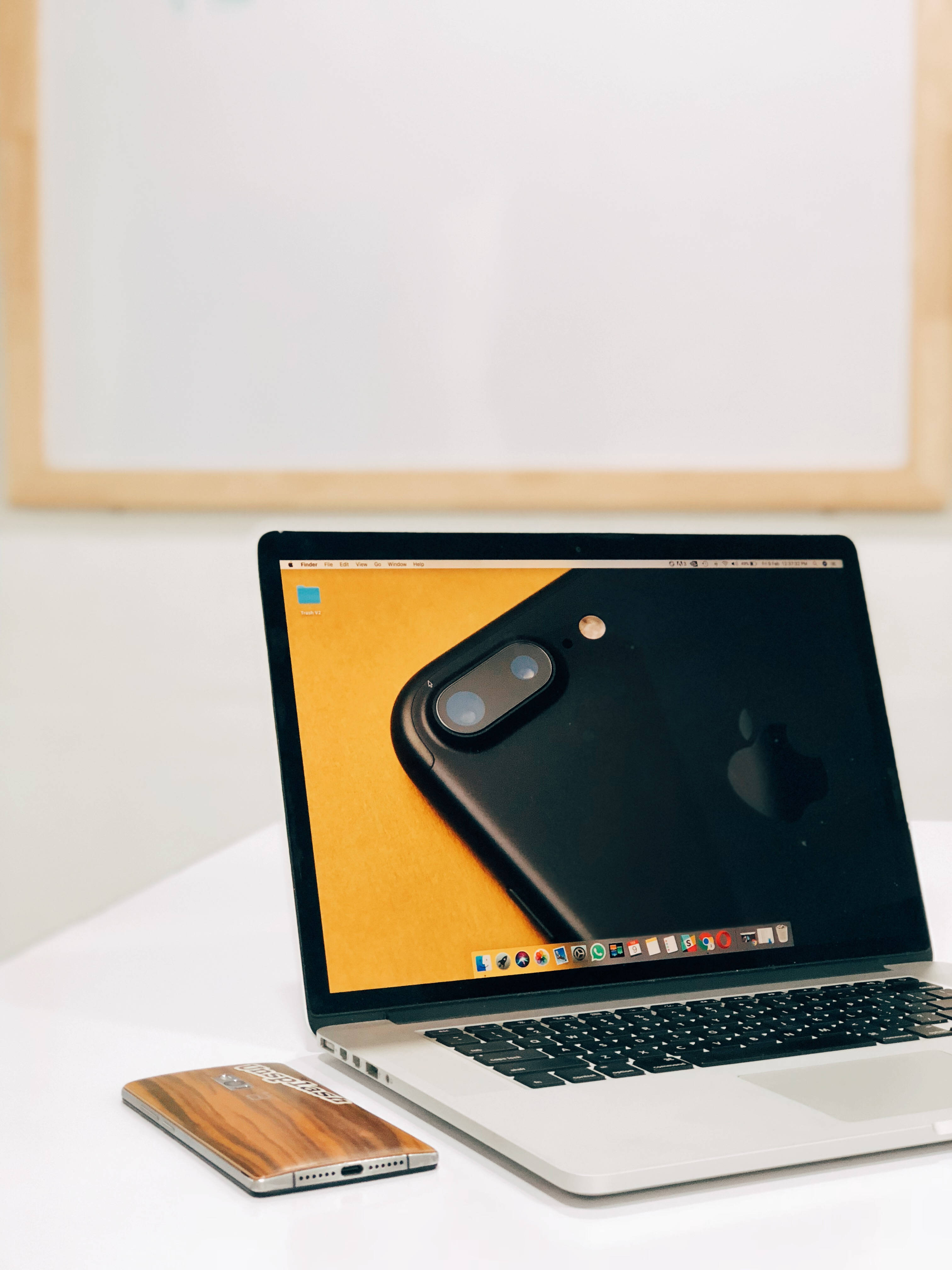 love computer 桌布 壁紙 — 一台時尚的銀色筆記型電腦在螢幕上顯示電話，旁邊有一個木製手機殼放在白色桌子上。