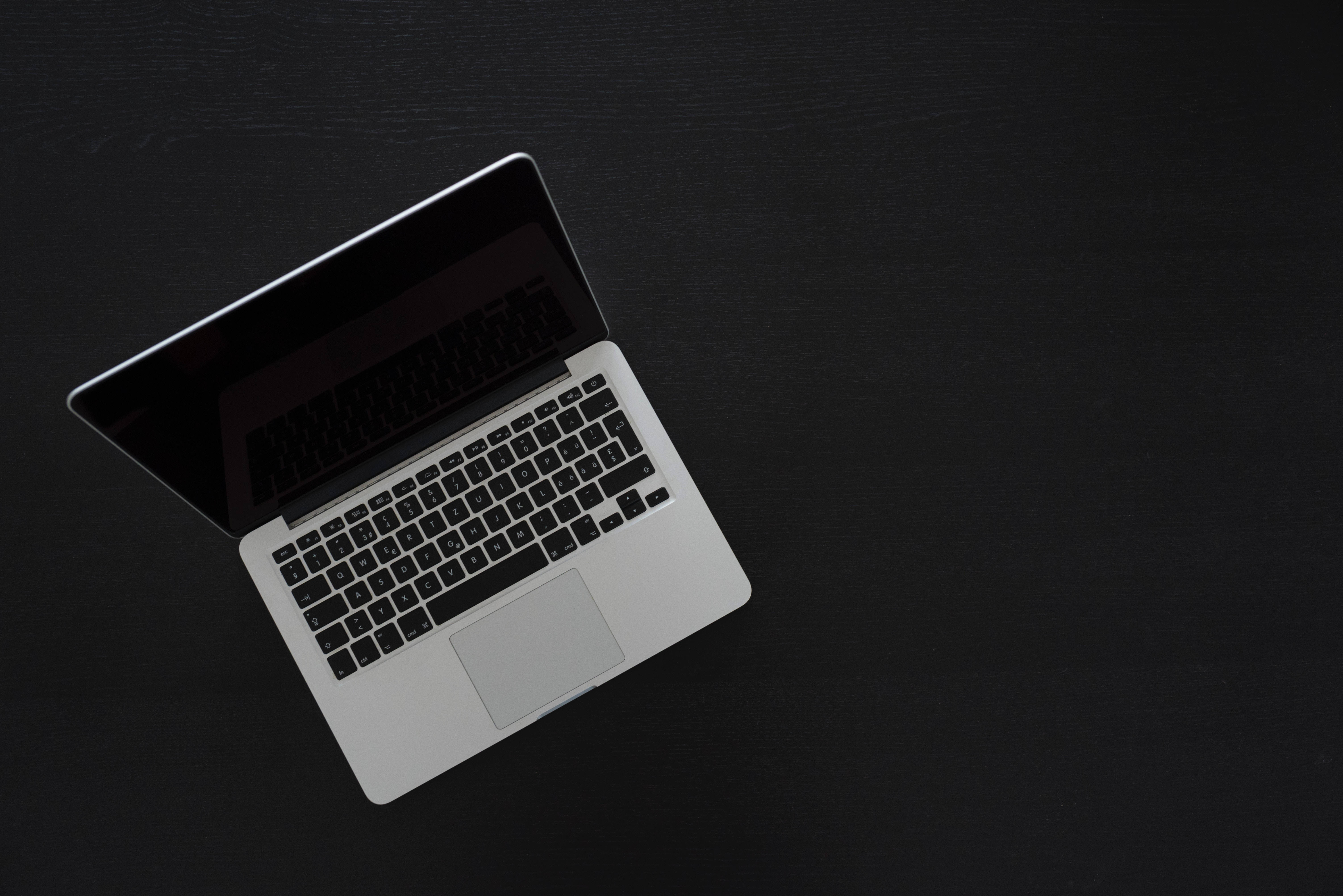 Cute Laptop 桌布 壁紙 — 一台時尚的銀色筆記型電腦打開放在霧面黑色紋理表面上，從上方觀看，構圖簡約。
