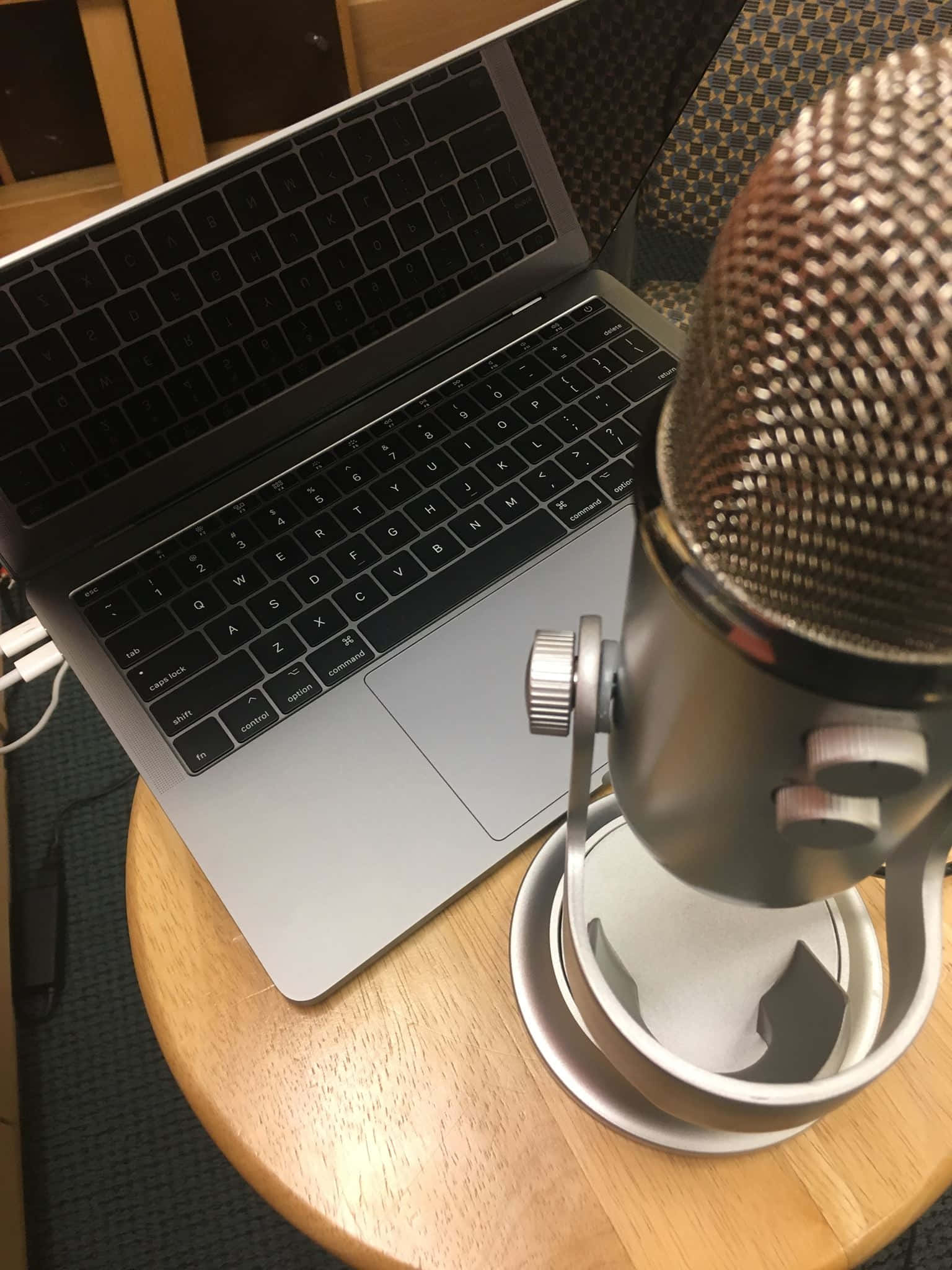 Podcasts 桌布 壁紙 — 一台時尚的銀色筆記型電腦旁邊放著一個專業錄音室麥克風，位於一個舒適的室內工作空間的木桌上。