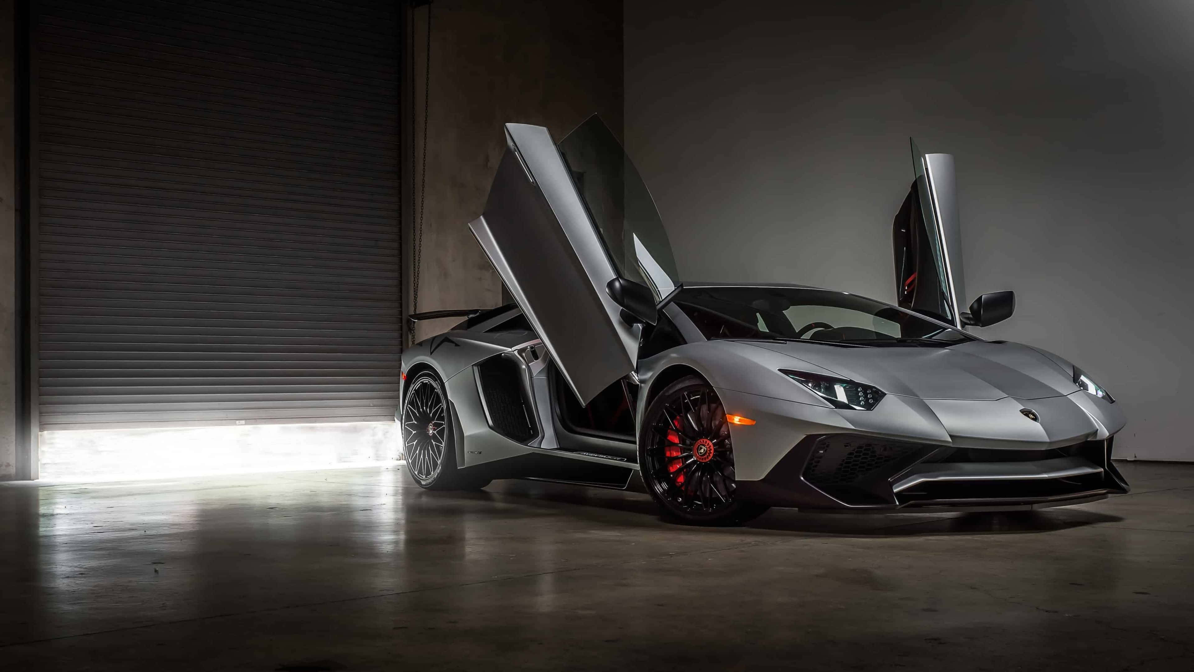 4K 藍寶堅尼 桌布 壁紙 — 一台時尚的銀色藍寶堅尼Aventador，車門向上開啟，在昏暗的車庫中，被關閉的鐵捲門射出的明亮燈光照耀下，顯得格外有氣勢。