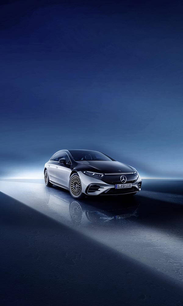 Mercedes 桌布 壁紙 — 一台時尚的銀色賓士轎車在夜間戲劇性的藍色燈光下，在反射的濕滑路面上滑行。