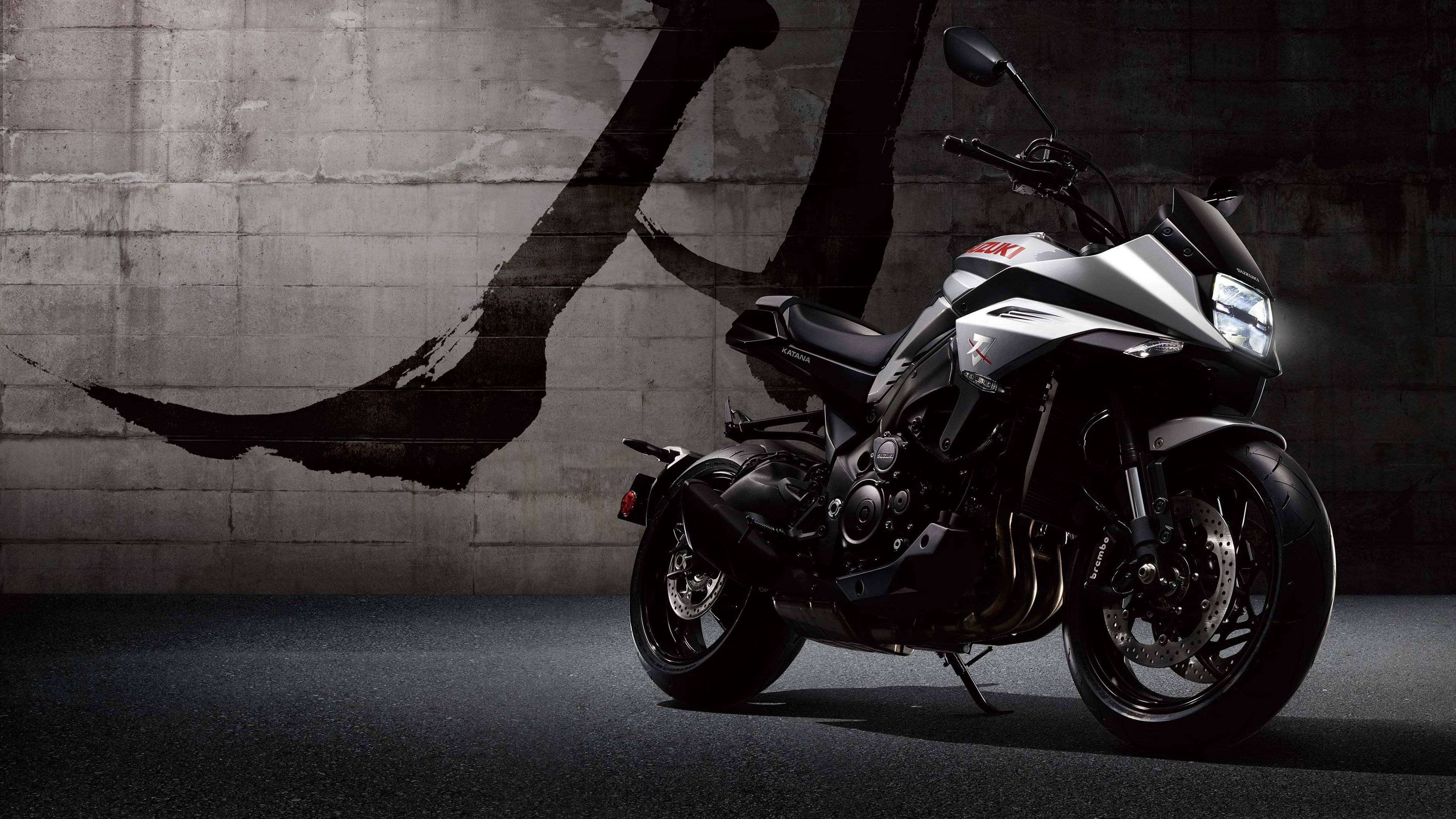 Suzuki 桌布 壁紙 — 一台時尚的銀黑色Suzuki機車，靠著一面飾有大膽黑色筆觸的粗糙混凝土牆。