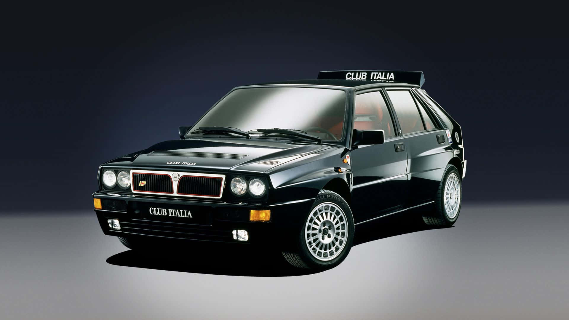 Lancia 桌布 壁紙 — 一台時尚的黑色 Lancia Delta Integrale 拉力賽車，帶有 'CLUB ITALIA' 貼花，置於深色漸變工作室背景前。