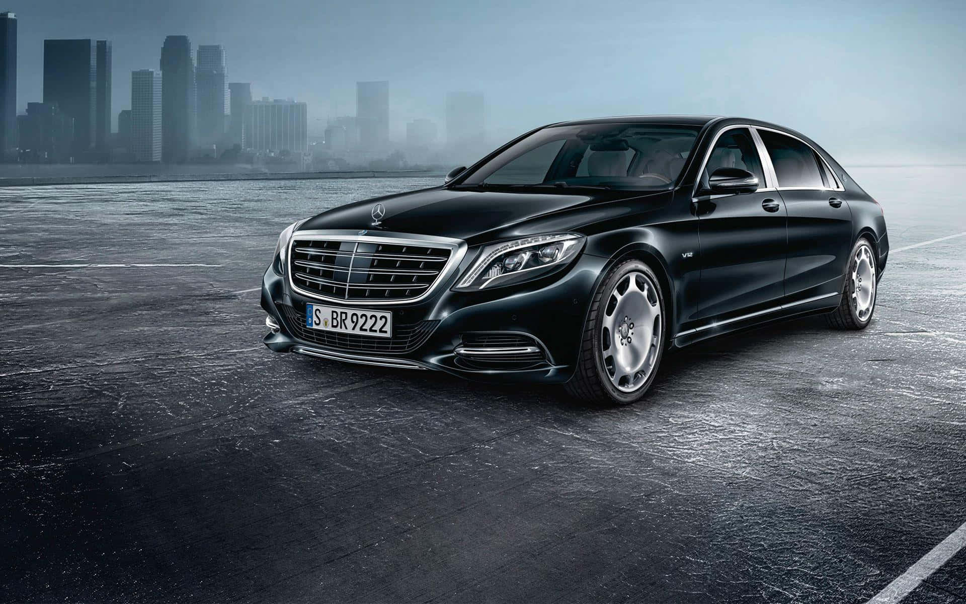 Maybach 桌布 壁紙 — 一台時尚的黑色 Mercedes-Maybach S-Class 轎車在濕漉漉的城市道路上閃耀，背景是朦朧的城市天際線。