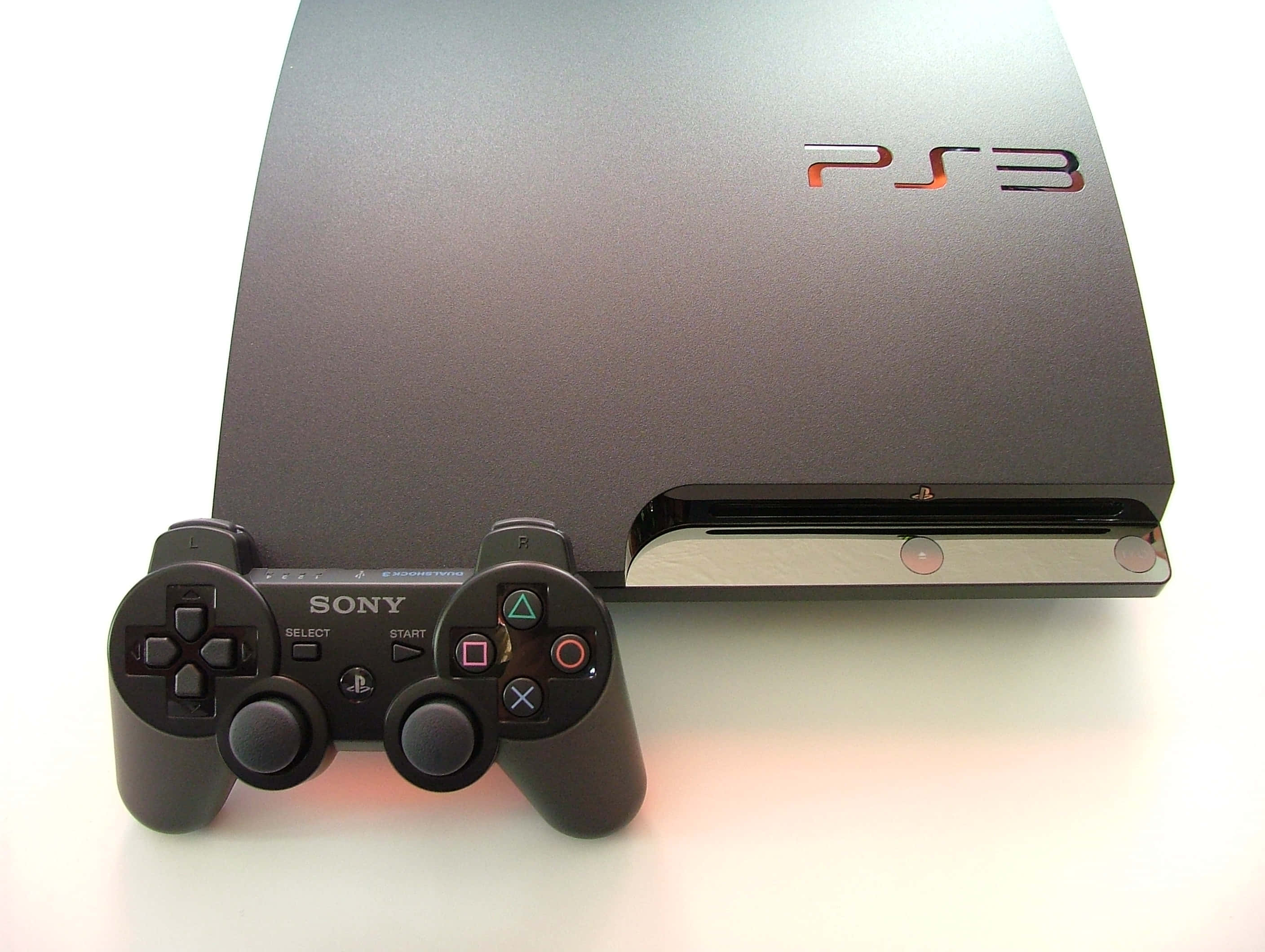 PlayStation 桌布 壁紙 — 一台時尚的黑色 PlayStation 3 主機及其控制器，在明亮的攝影棚燈光下，放置在潔白的表面上。