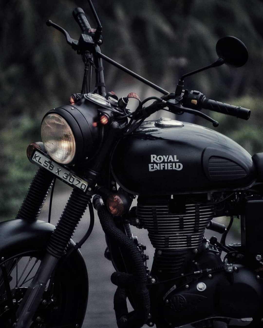 Royal 桌布 壁紙 — 一台時尚的黑色 Royal Enfield 摩托車，車頭燈亮著，停在公路上，背景是模糊的森林。