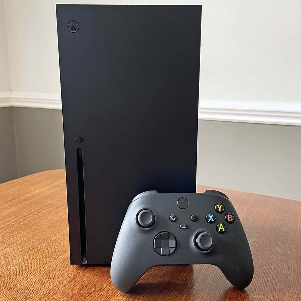 Xbox 桌布 壁紙 — 一台時尚的黑色 Xbox Series X 主機和控制器放在溫暖的木桌上，背景是中性牆壁。