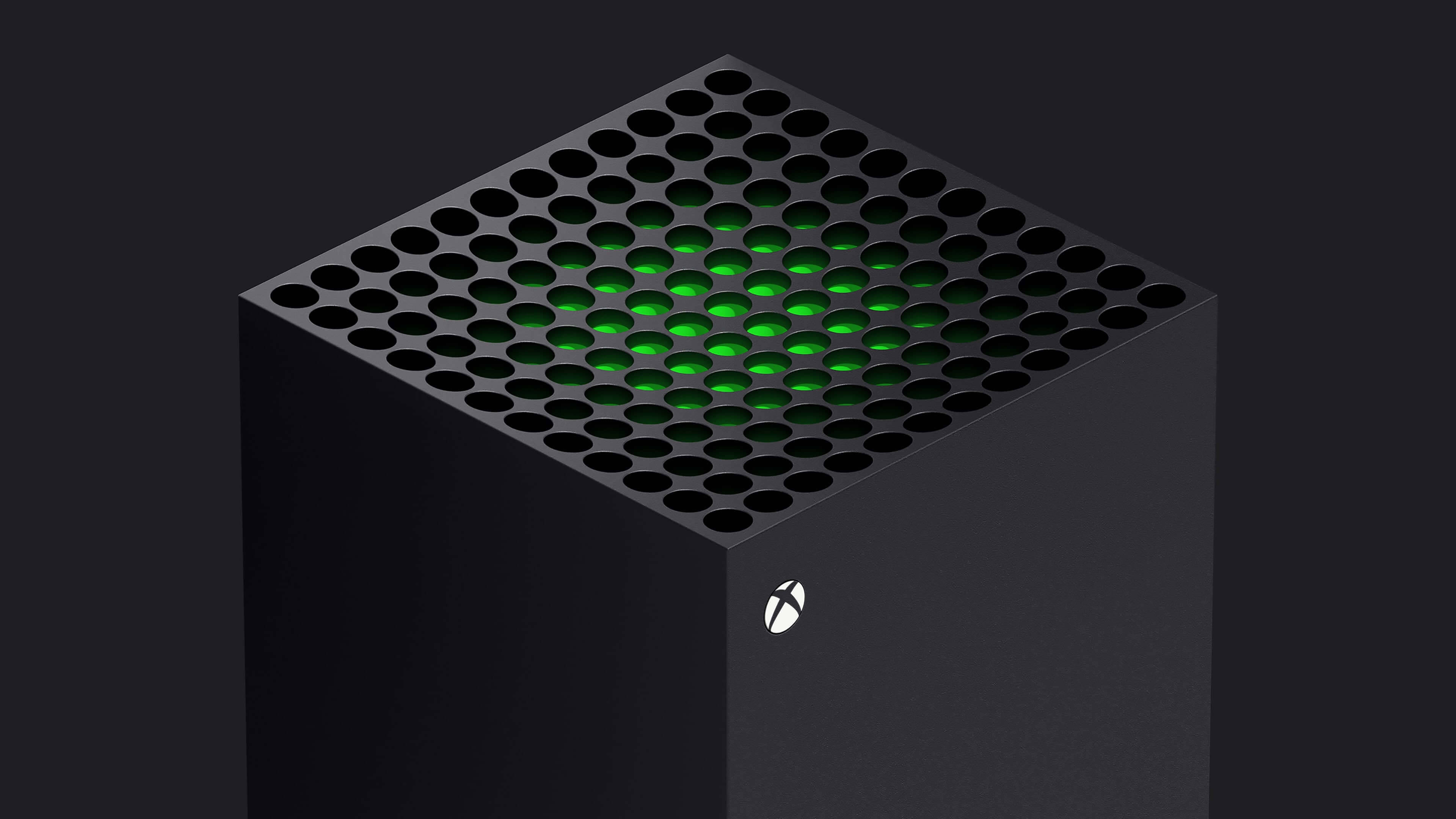 X 桌布 壁紙 — 一台時尚的黑色 Xbox Series X 主機，透過穿孔頂板發出綠色 LED 光芒，背景為深色。
