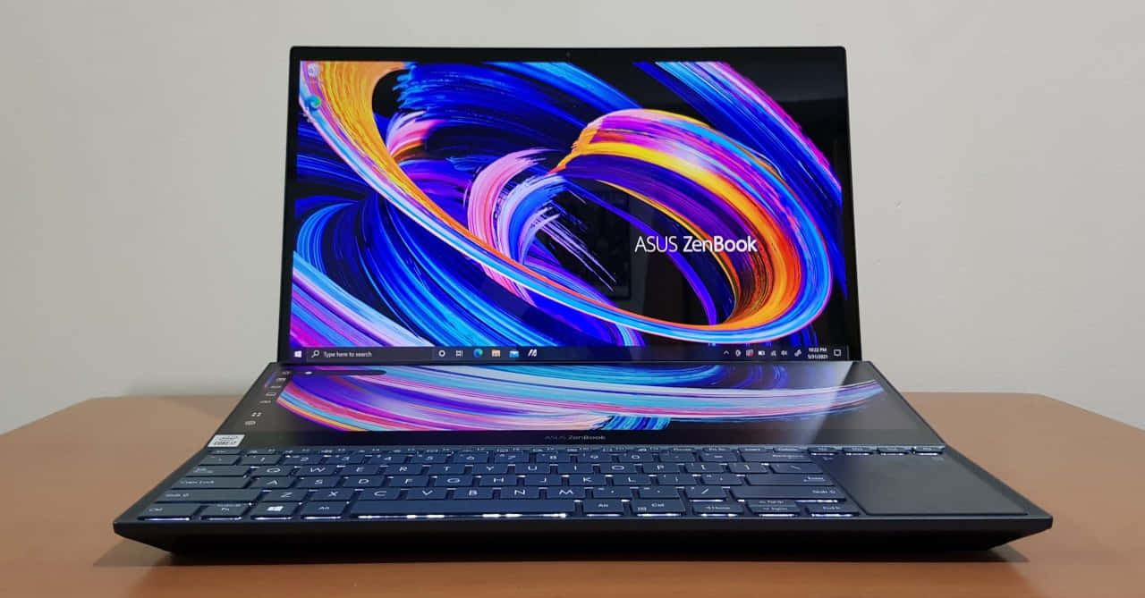 ASUS 桌布 壁紙 — 一台時尚的黑色ASUS ZenBook筆記型電腦在木桌上展示著充滿活力的旋轉抽象桌布。