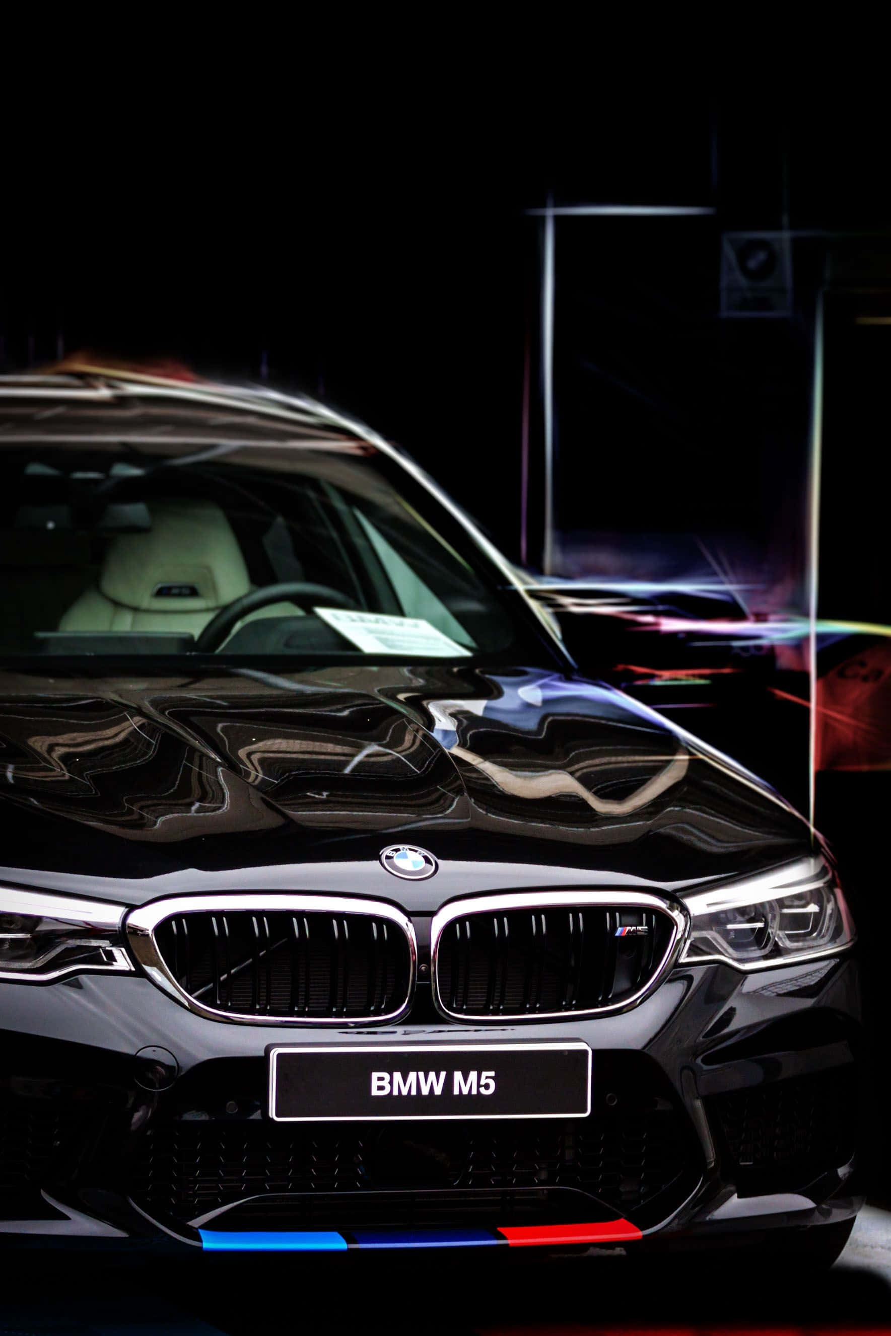 Bmw Cars 桌布 壁紙 — 一台時尚的黑色BMW M5跑車在戲劇性的攝影棚燈光下閃耀，背景中充滿活力的霓虹反射。