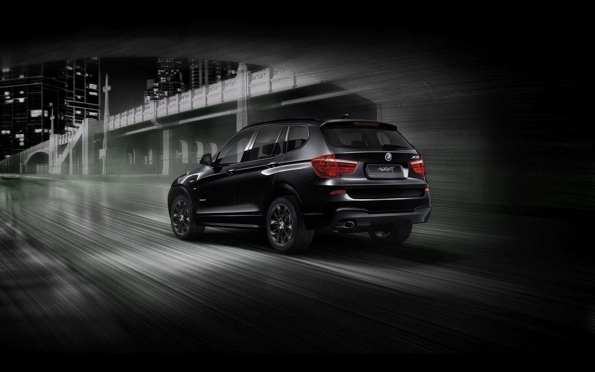 Bmw X3 桌布 壁紙 — 一台時尚的黑色BMW SUV在濕滑的市區隧道中疾馳，帶有動態模糊和發光的紅色尾燈。