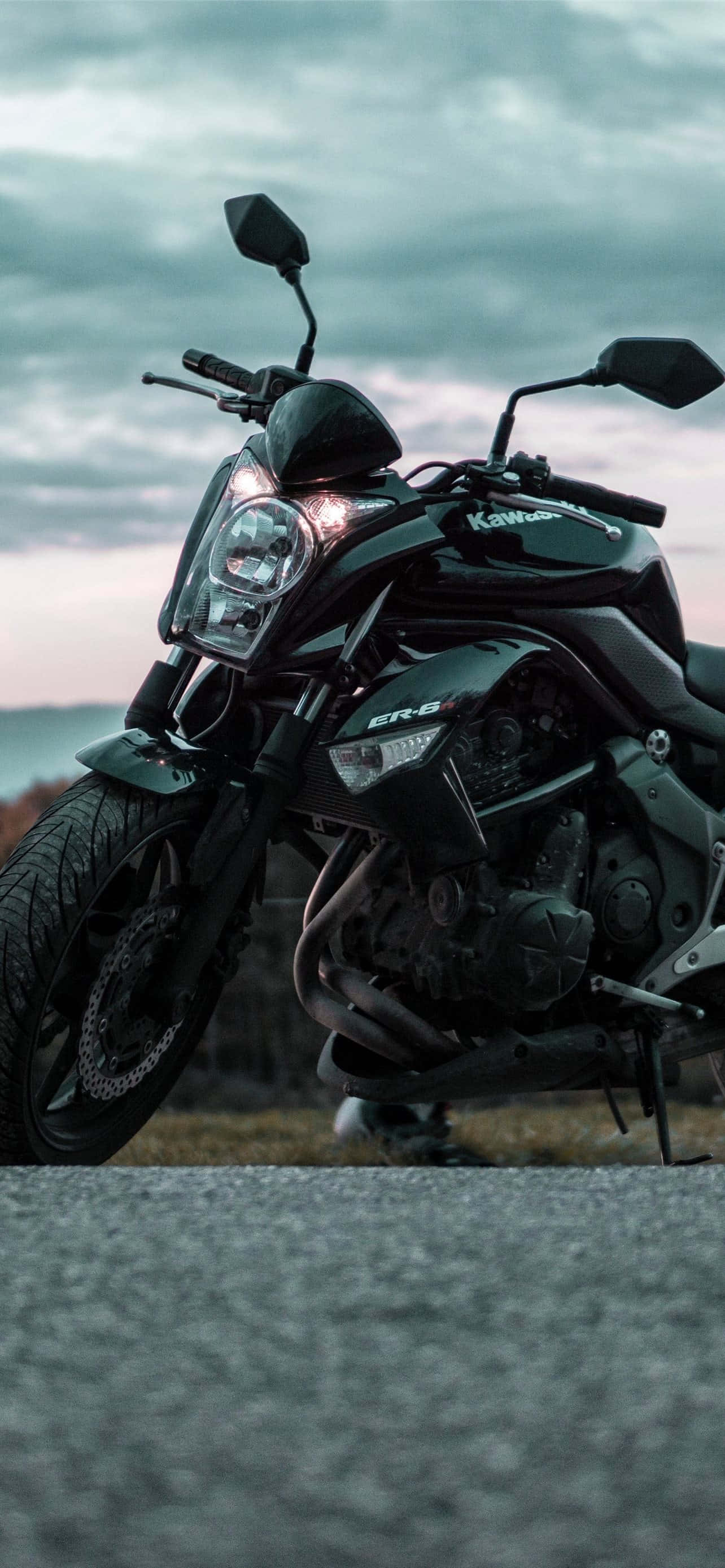 機車 桌布 壁紙 — 一台時尚的黑色Kawasaki ER-6機車，在陰沉的暮色天空下，停在碎石路上。
