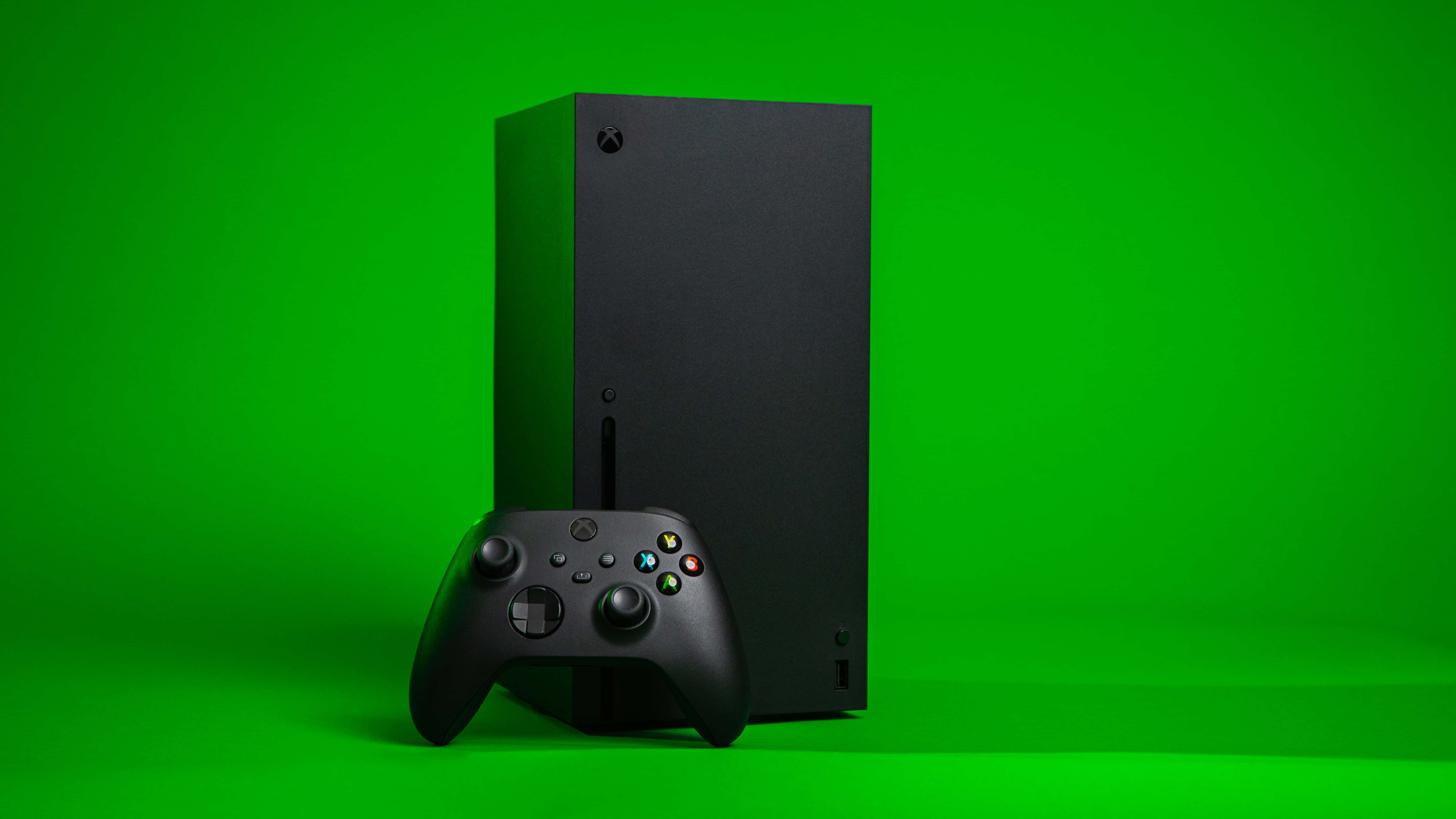 Gaming Consoles 桌布 壁紙 — 一台時尚的黑色Xbox Series X主機和控制器，在充滿活力的綠色工作室背景前矗立。