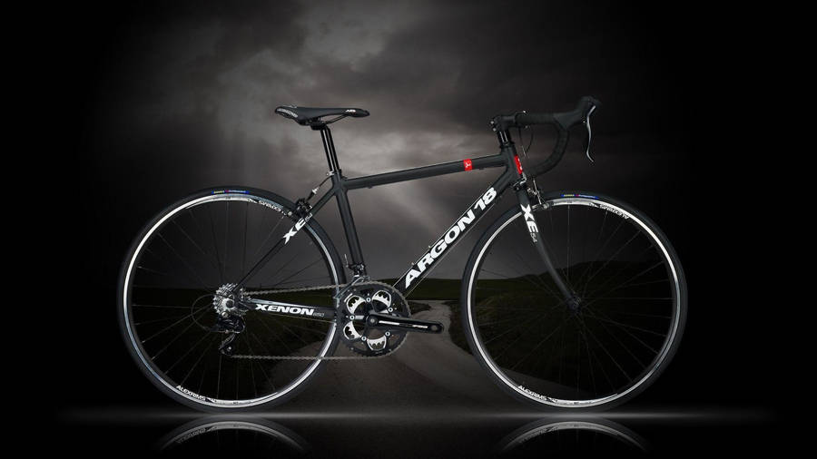 桌布 壁紙 — 一台時尚的黑色Xenon Argon 18公路自行車，在黑暗暴風雨的天空和反射地面的襯托下，顯得格外突出。