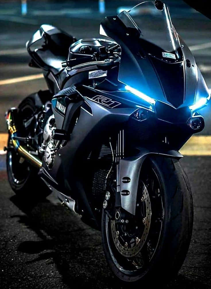 腳踏車 桌布 壁紙 — 一台時尚的黑色Yamaha R1機車在夜間濕滑的城市街道上，在霓虹燈下閃閃發光。