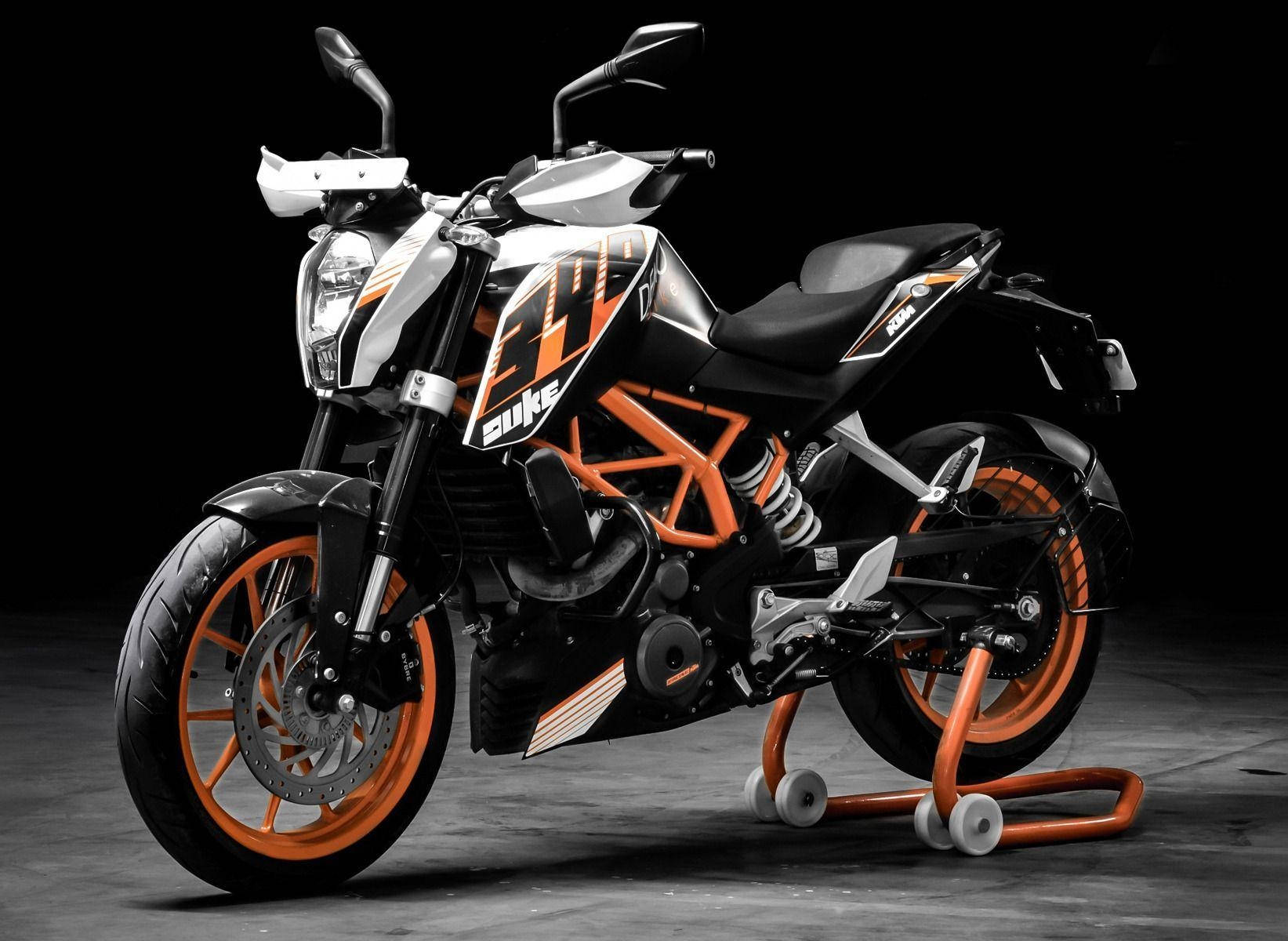 motorbike 桌布 壁紙 — 一台時尚的黑色和橙色KTM Duke摩托車在深色攝影棚背景前立於支架上。