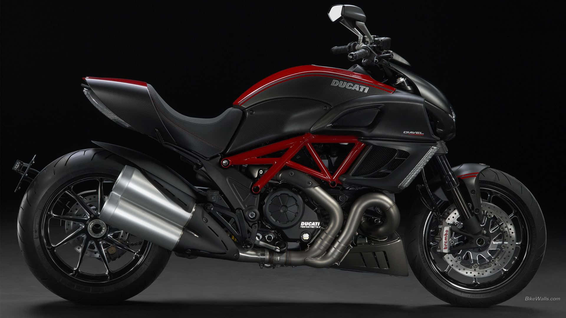 HD Bikes 桌布 壁紙 — 一台時尚的黑色和紅色Ducati摩托車，帶有外露的紅色編織車架和鍍鉻排氣管，在深色攝影棚背景下展示。