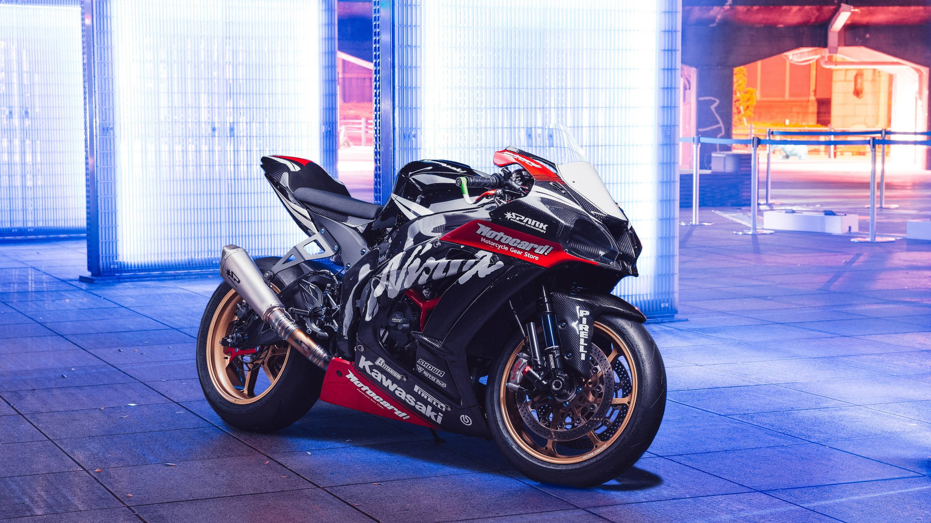 機車 桌布 壁紙 — 一台時尚的黑色和紅色Kawasaki Ninja運動機車在現代都市環境中，在充滿活力的藍色霓虹燈下閃閃發光。