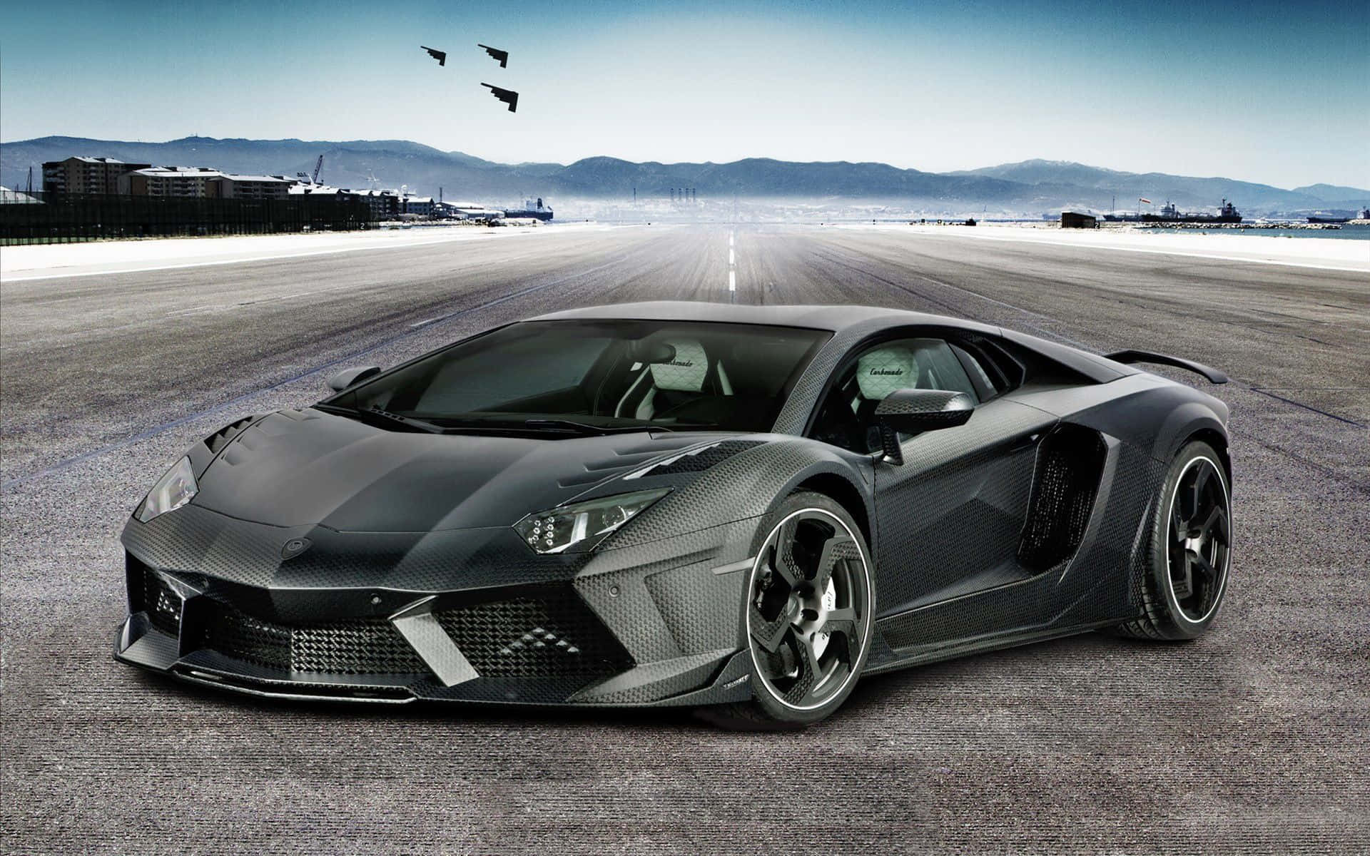 跑車 桌布 壁紙 — 一台時尚的黑色碳纖維藍寶堅尼 Aventador 停放在廣闊的機場跑道上，遠方有山脈，戰鬥機在頭頂呼嘯而過。