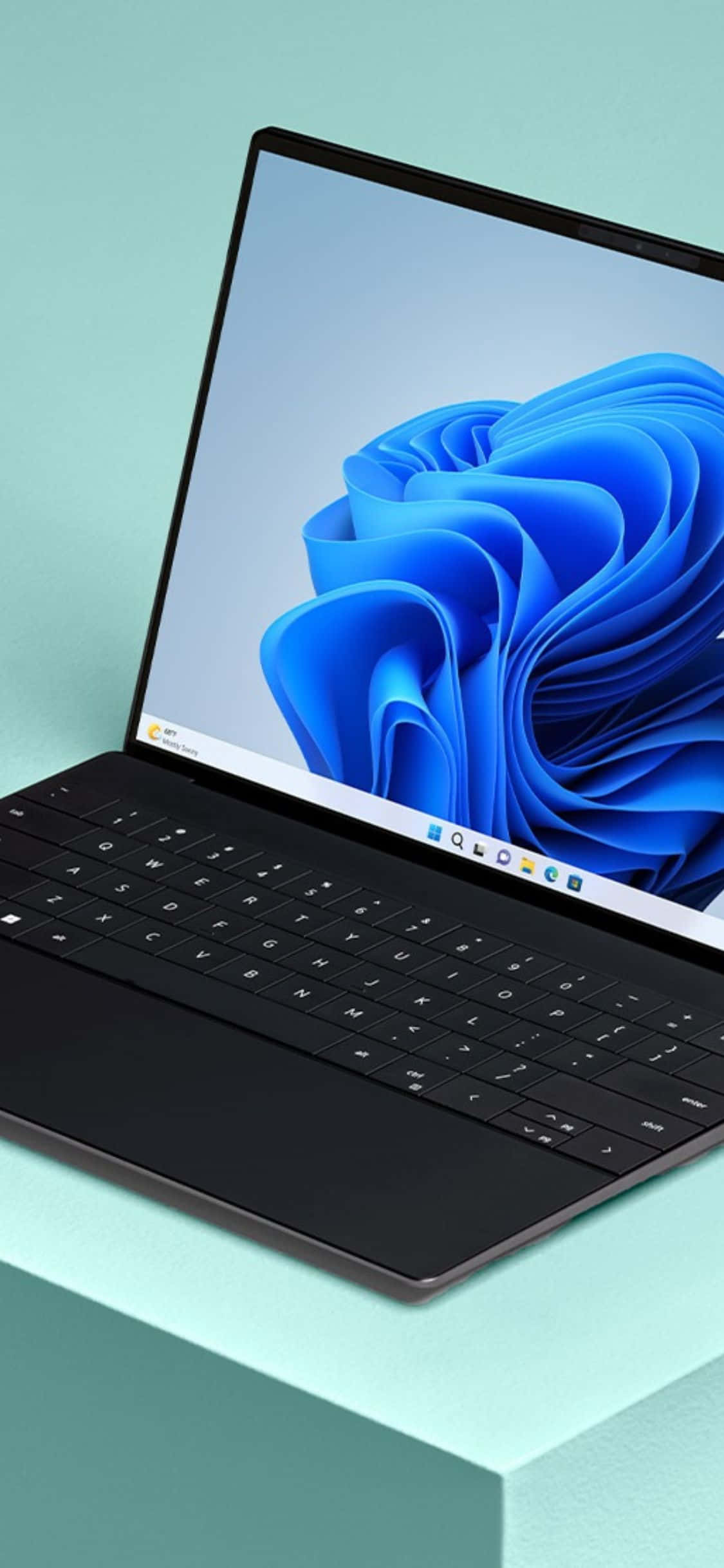 iPhone Xs Computer 桌布 壁紙 — 一台時尚的黑色筆記型電腦在柔和的薄荷綠色背景上顯示鮮豔的藍色抽象花卉桌布。