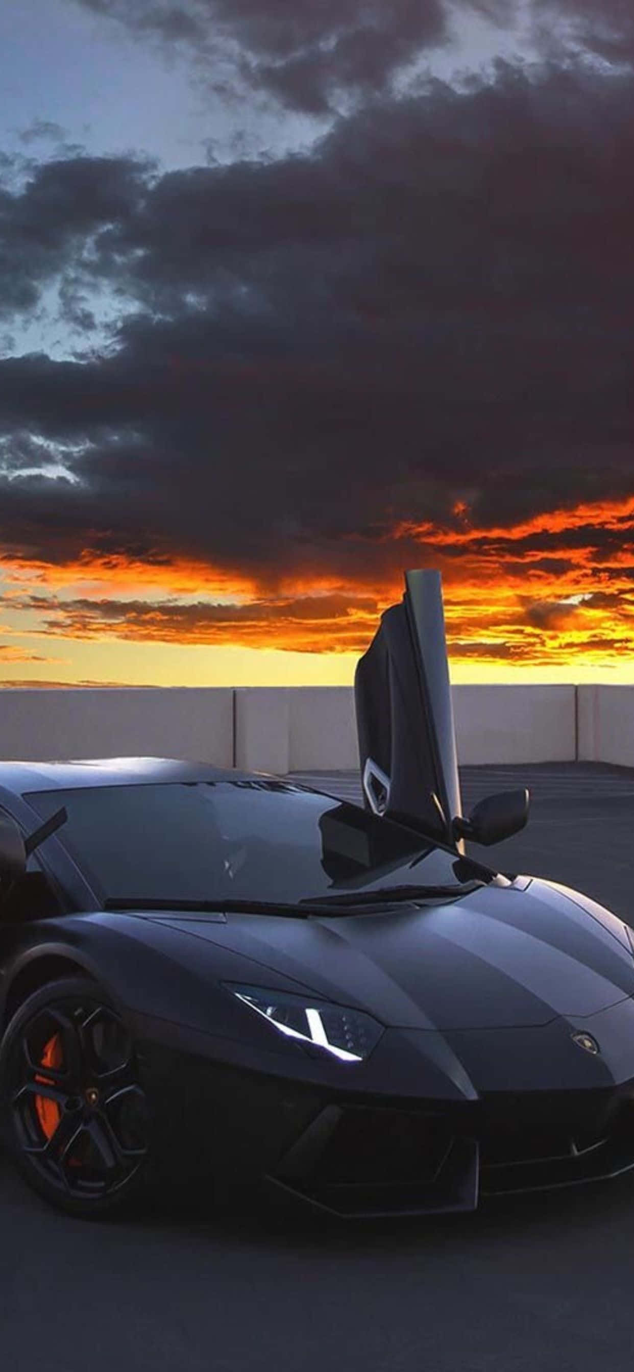 Lamborghini Phone 桌布 壁紙 — 一台時尚的黑色藍寶堅尼，剪刀門打開，矗立在戲劇性的日落天空前，天空中有火紅的橙色雲彩。